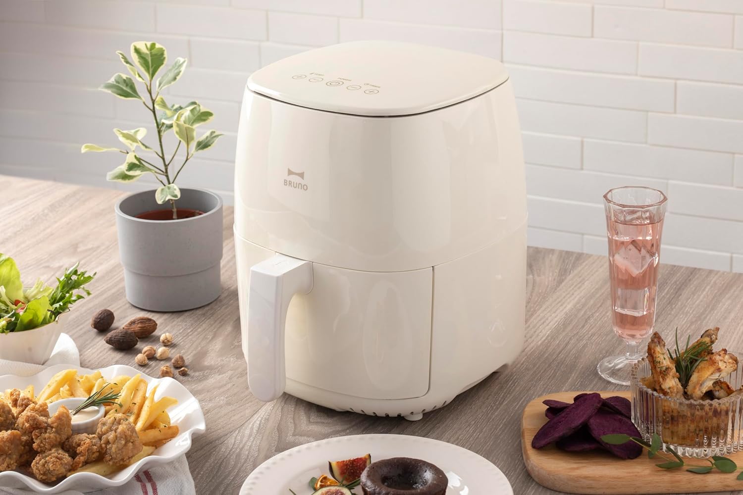 BRUNO Compact Air Fryer in a kitchen setting with various cooked foods