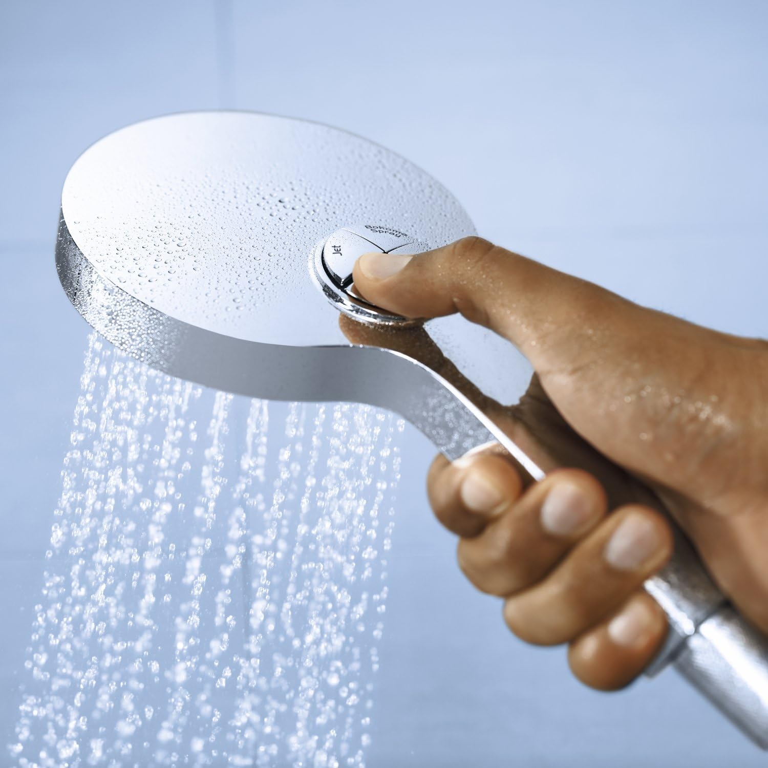 Hand pressing the spray selection button on the GROHE Power and Soul Cosmopolitan 130 Hand Shower to change the spray pattern.