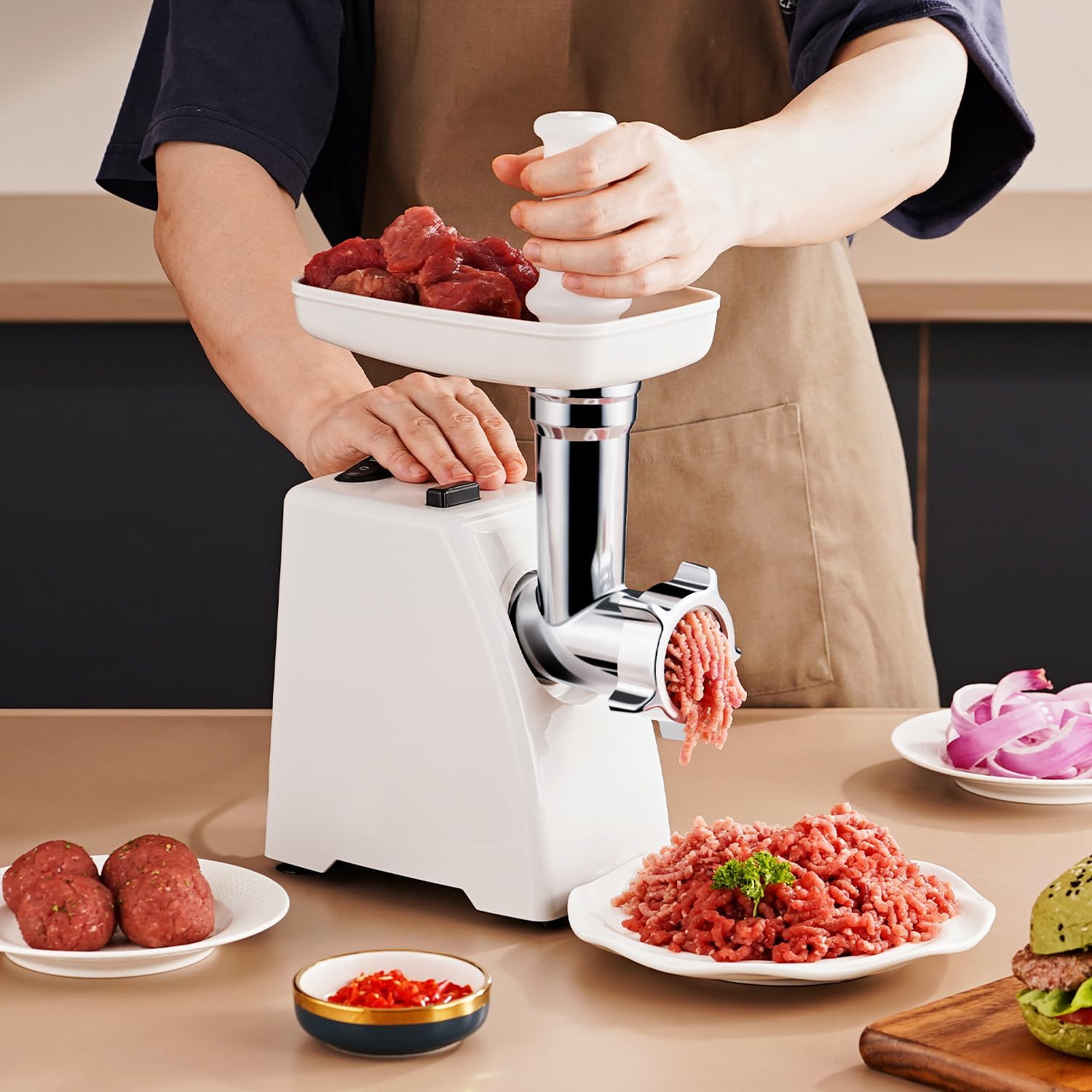A person using the AMZCHEF meat mincer to grind meat, feeding pieces into the hopper with the food pusher while ground meat exits the grinding head.