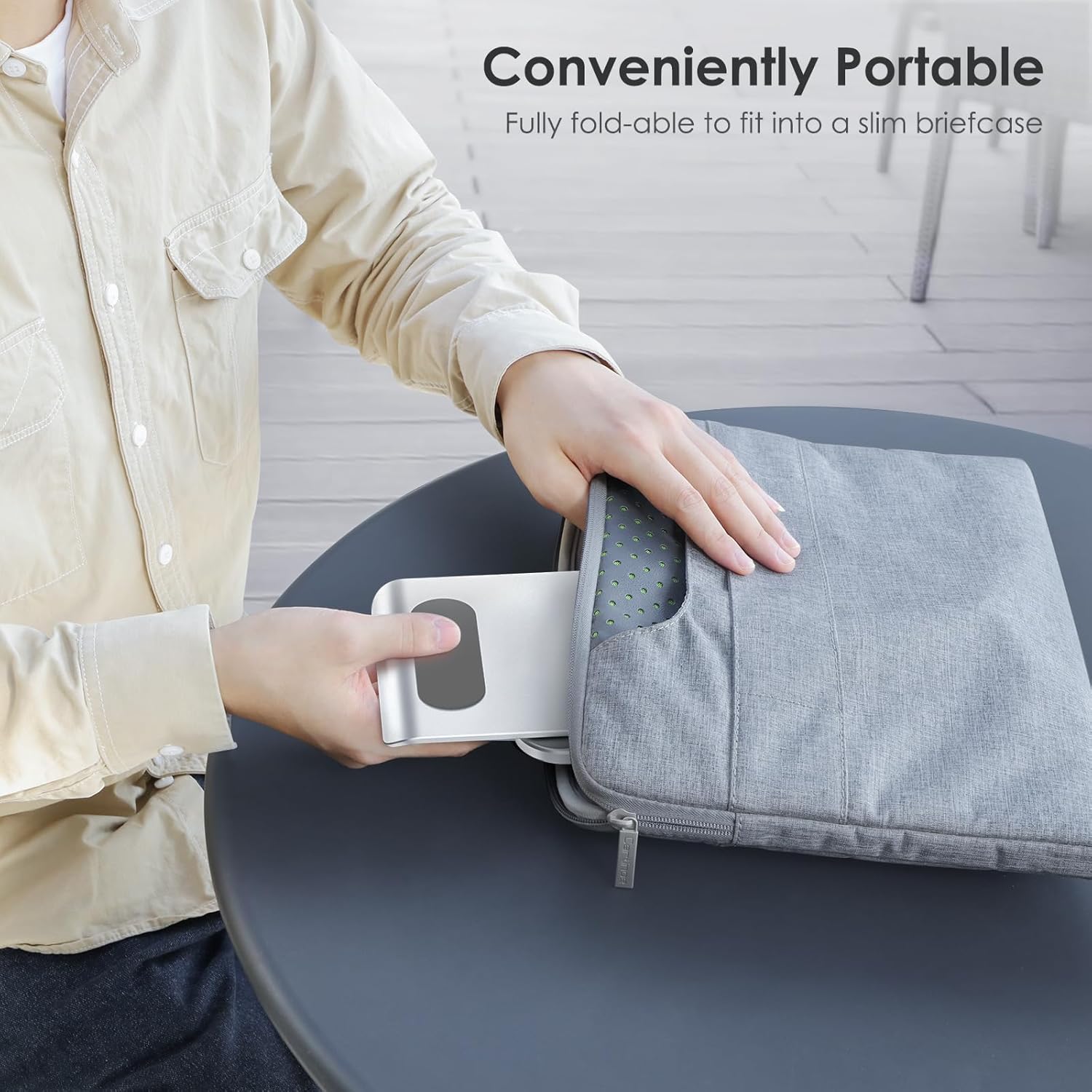 A hand sliding the folded OMOTON T5 stand into a laptop bag, demonstrating its portability.