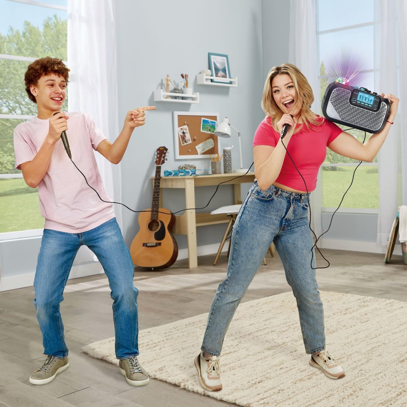 Two young adults singing into microphones with the VTech Super Sound Karaoke machine, showing party lights in action