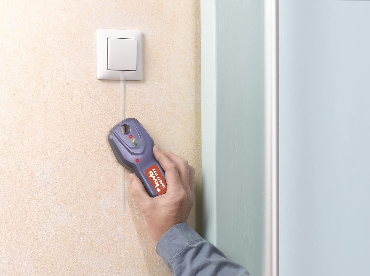 A hand holding the KWB Safety-Fixx detector near an electrical outlet, detecting a live wire.