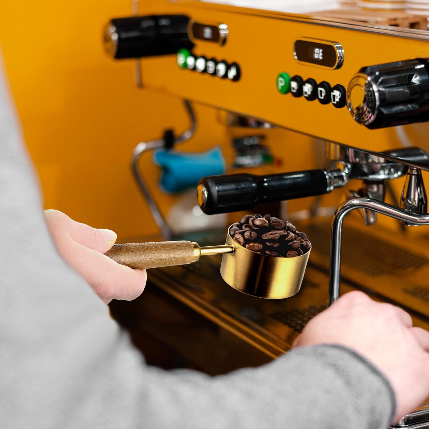 Hand holding KALIONE Measuring Scoop near coffee machine