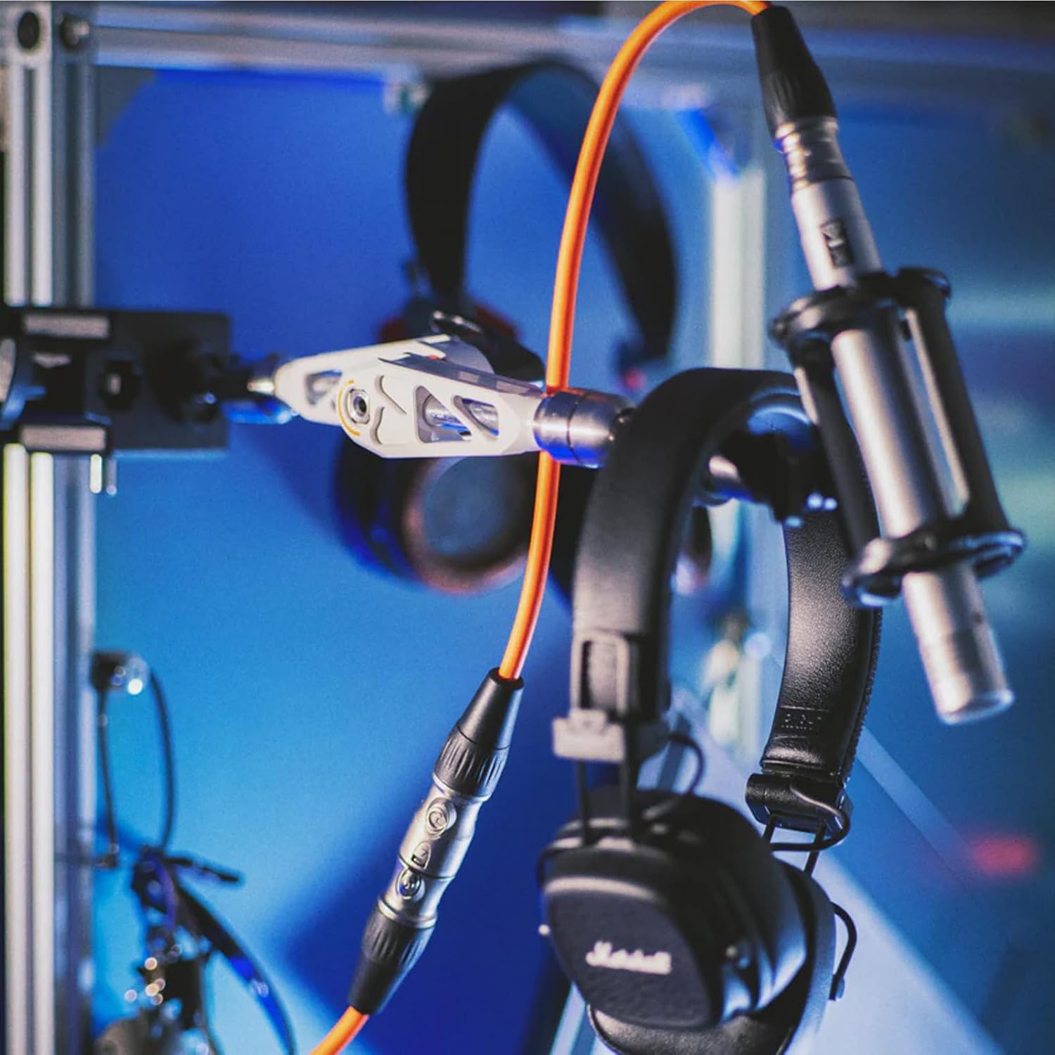 MOFAGE Talos Damping Magic Arm holding headphones and a microphone, demonstrating its versatility.