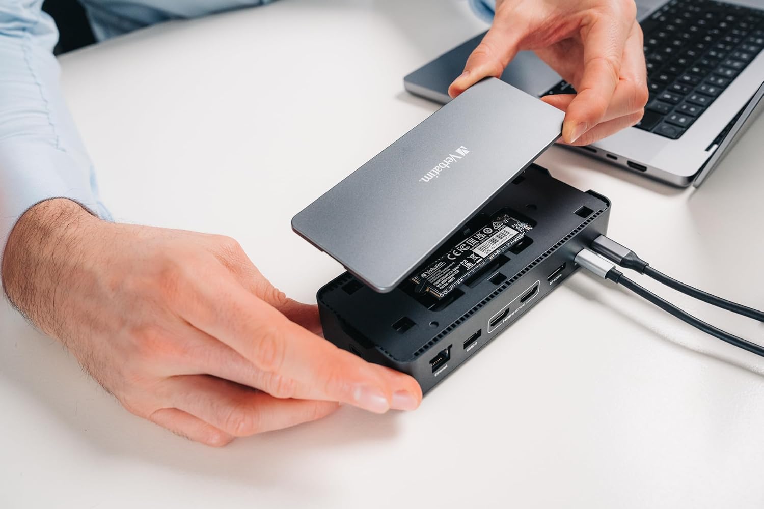Hands demonstrating the installation or removal of the SSD cover on the Verbatim USB-C Pro Docking Station.