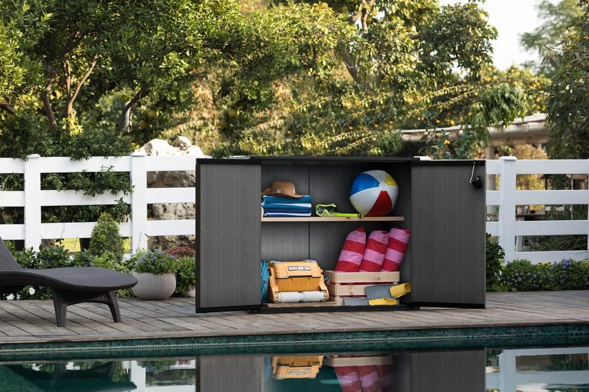 Caixa d'emmagatzematge Keter Cortina Bella oberta al costat d'una piscina, per emmagatzemar accessoris de piscina