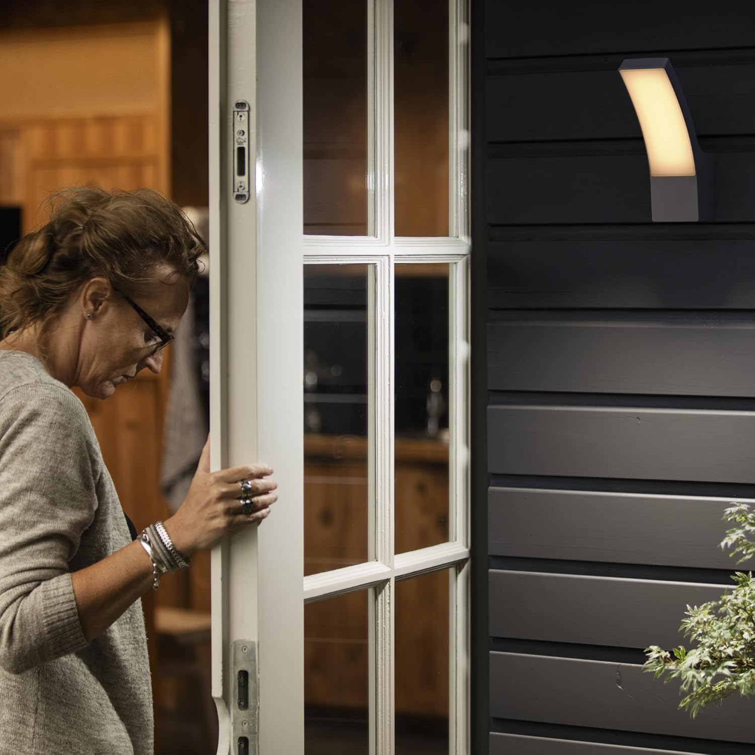 Philips Splay LED Outdoor Wall Light illuminating an entrance at night, with a person opening a door.