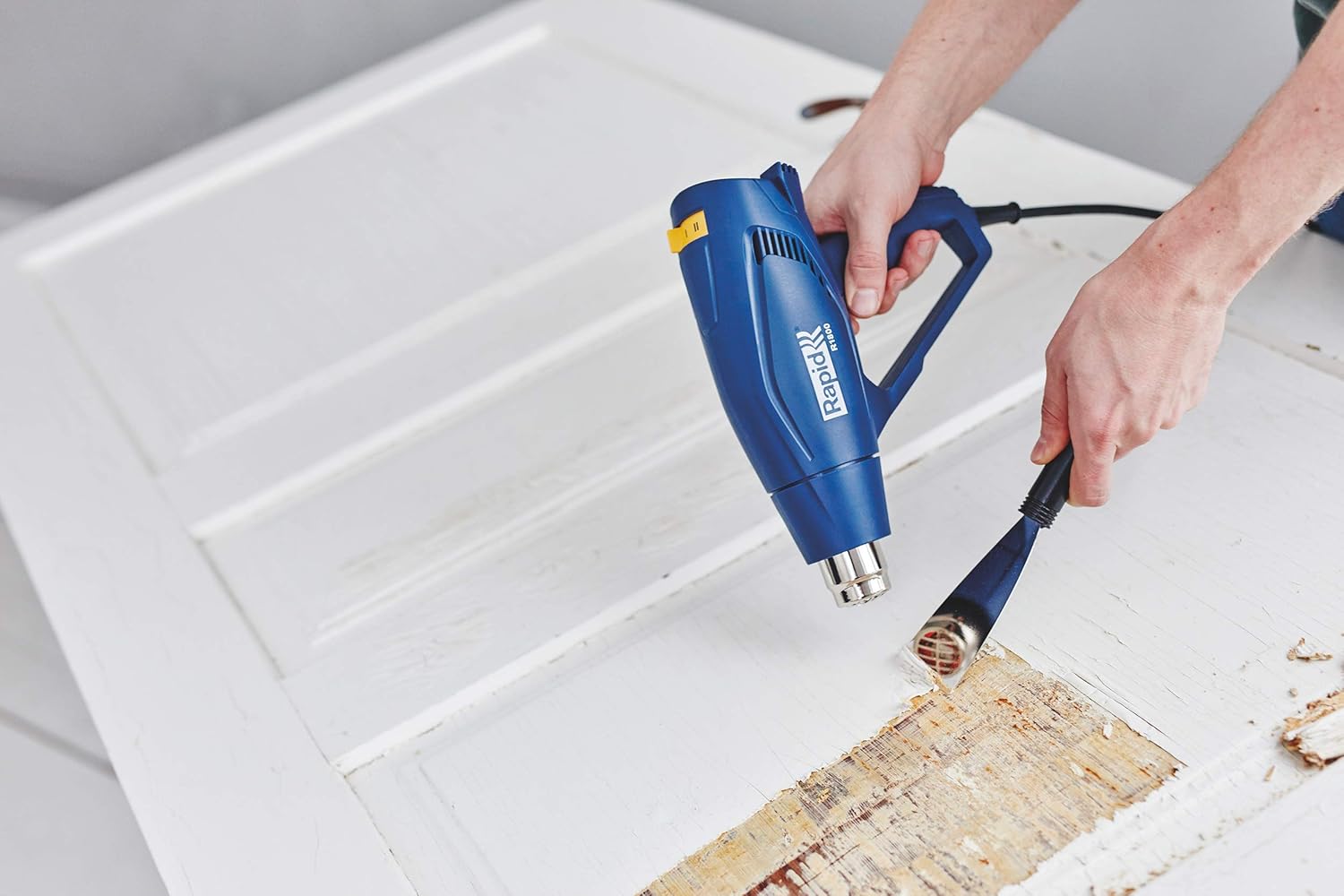 Person using Rapid R1800 Hot Air Gun to remove paint from a wooden door