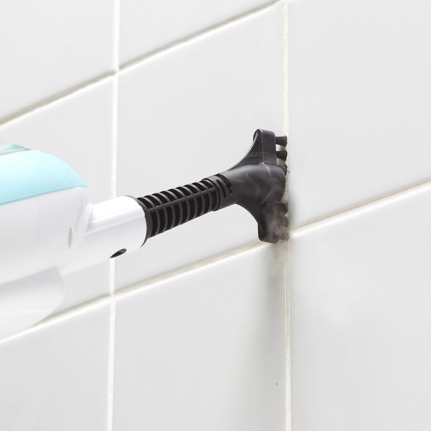 Handheld steamer cleaning tile grout with grout brush