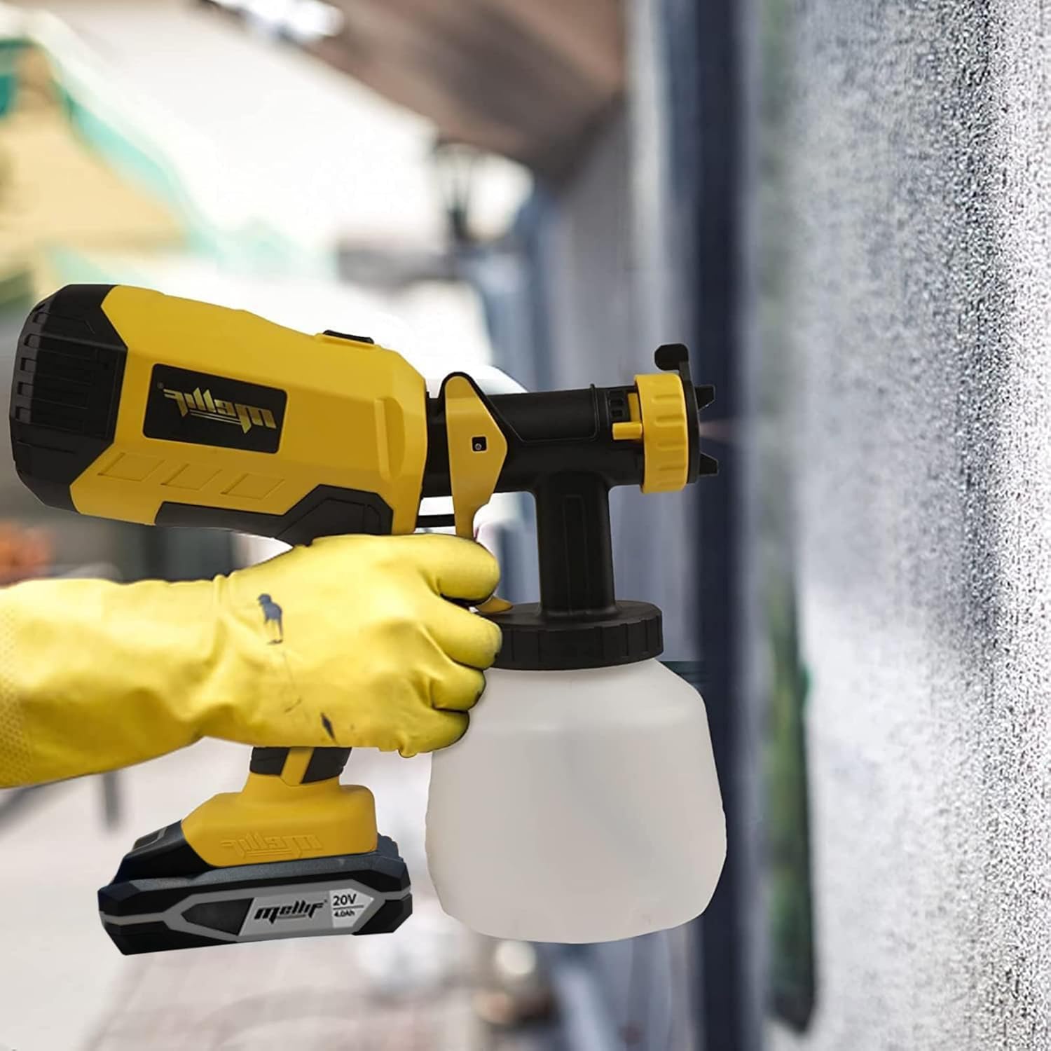 A person wearing yellow gloves using the Mellif paint sprayer to apply paint to an exterior wall, showing cordless operation.