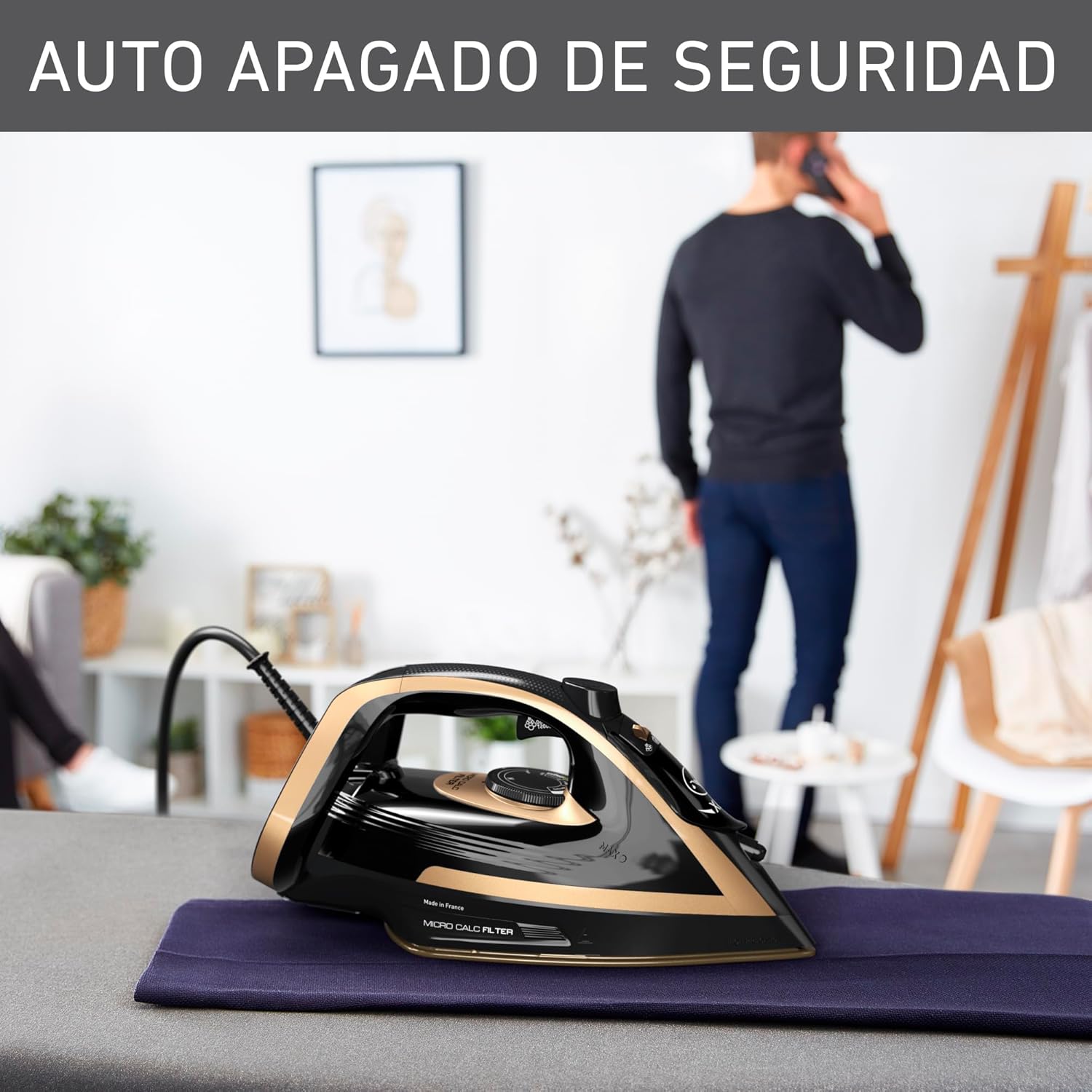 T-fal Puregliss Steam Iron FV8064X0 on an ironing board, illustrating the auto-off safety feature with a person in the background.