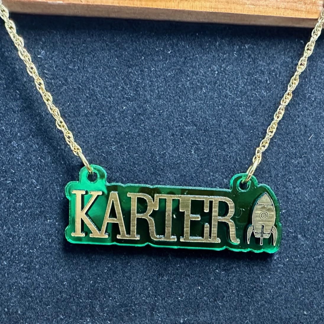 Sports Fan Player Gamer Themed Nameplate Necklace with Gold Laser Cut Letters and Rocketship on Green Mirror Background with Gold Chain Personalized Made to Order Custom Any Name Great Gift Idea Made in CT, USA