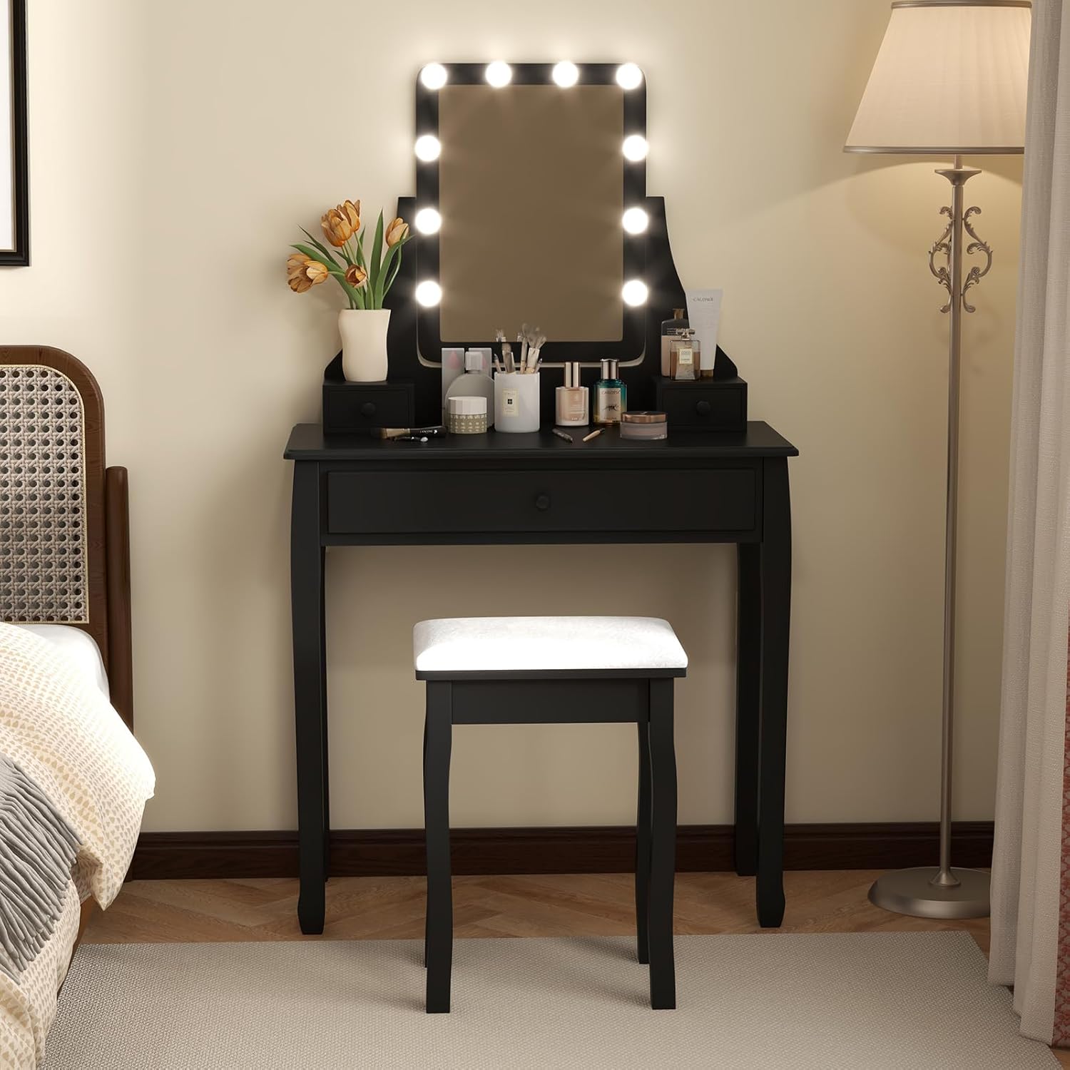 Assembled black vanity desk with lighted mirror and cushioned stool in a bedroom setting.