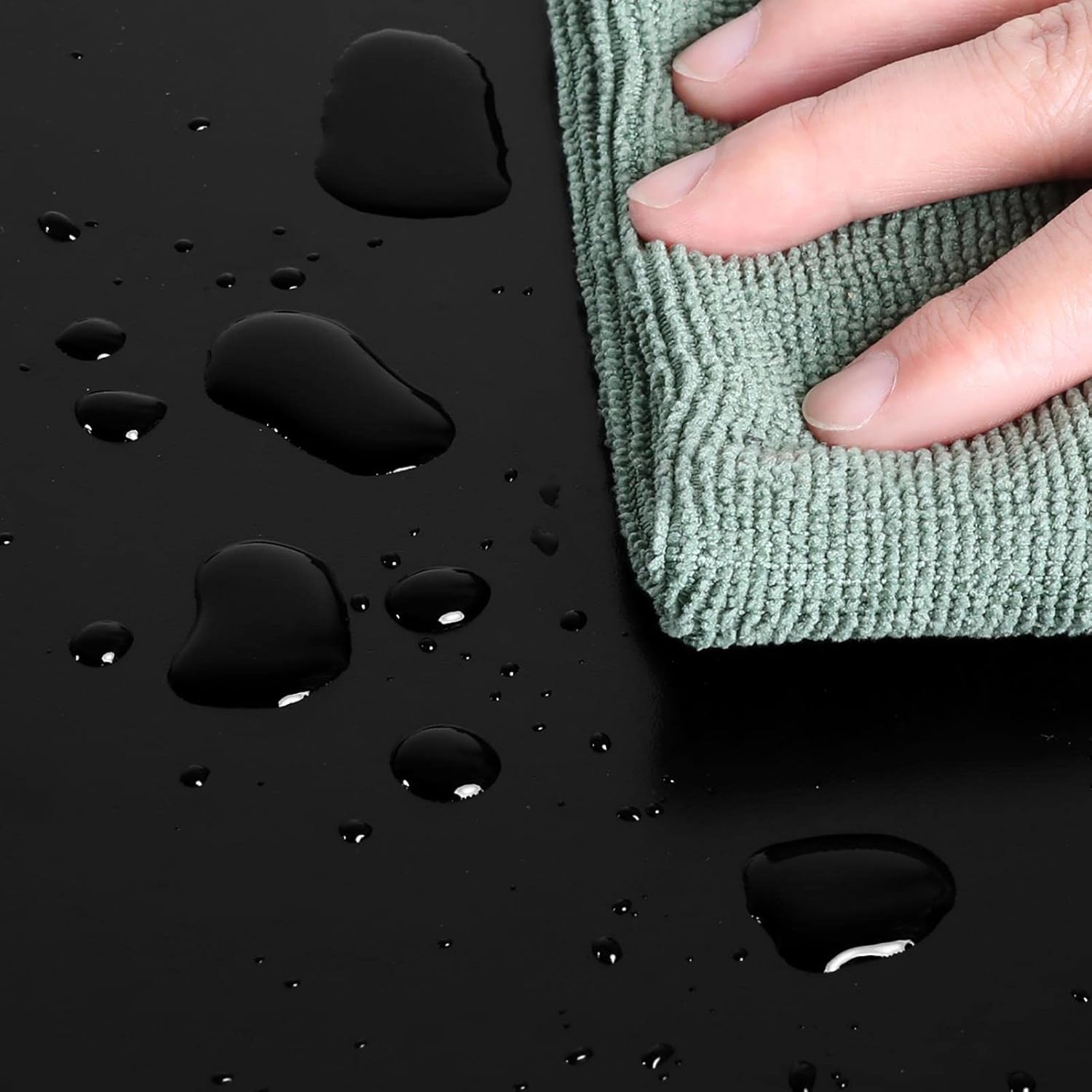 Hand wiping water droplets from the nightstand surface with a cloth.