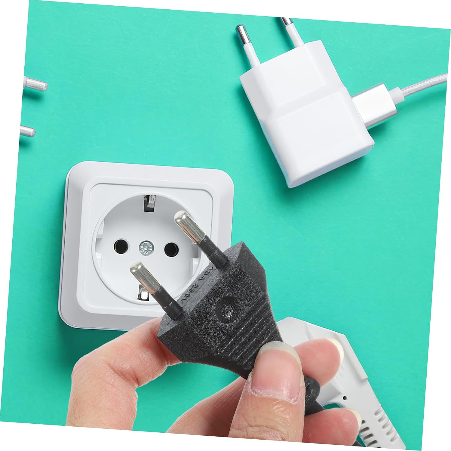 Hand holding the 2-pin plug near a wall socket