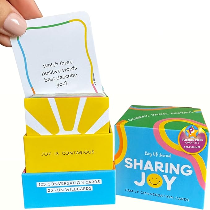 Sharing Joy conversation cards by Big Life Journal, featuring 125 family-friendly prompts and 25 wildcard questions. Includes colorful packaging with an open card reading “Which three positive words best describe you?” Ideal for caregivers, seniors, and families looking to boost social connection, emotional wellness, and meaningful conversation. Great tool for memory care and reducing senior isolation.