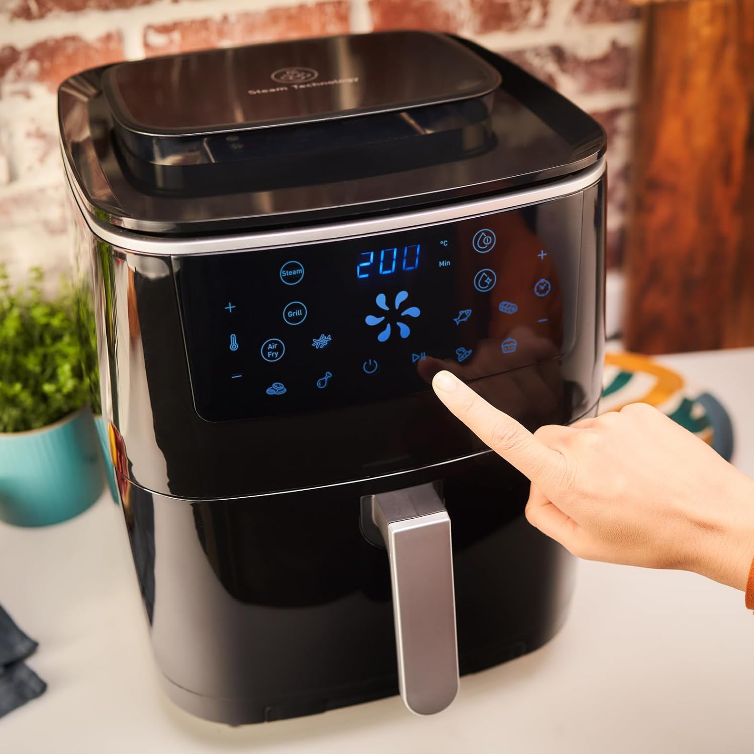 Hand touching the digital control panel of Tefal FW2018 Easy Fry Grill & Steam
