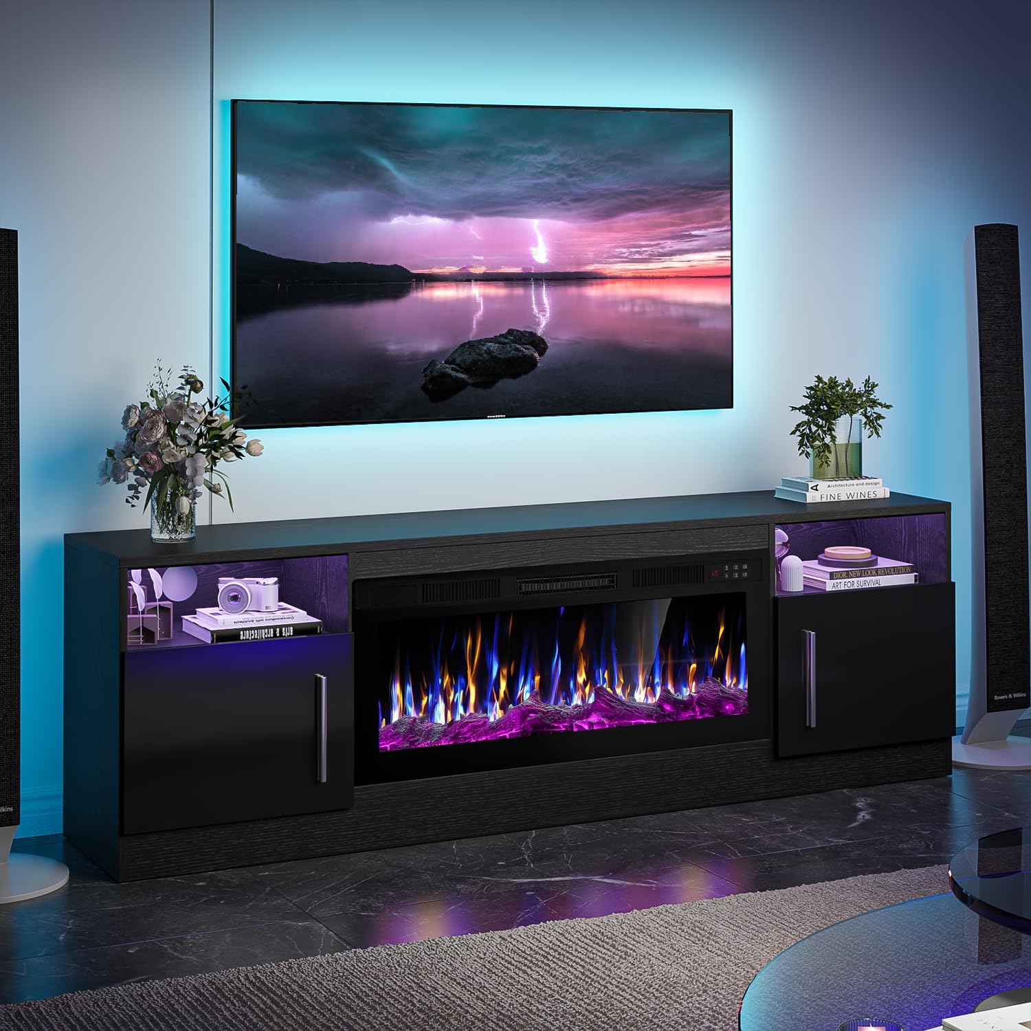A VITESSE 70-inch Electric Fireplace TV Stand in black with blue LED lighting and a colorful flame effect, supporting a large TV.