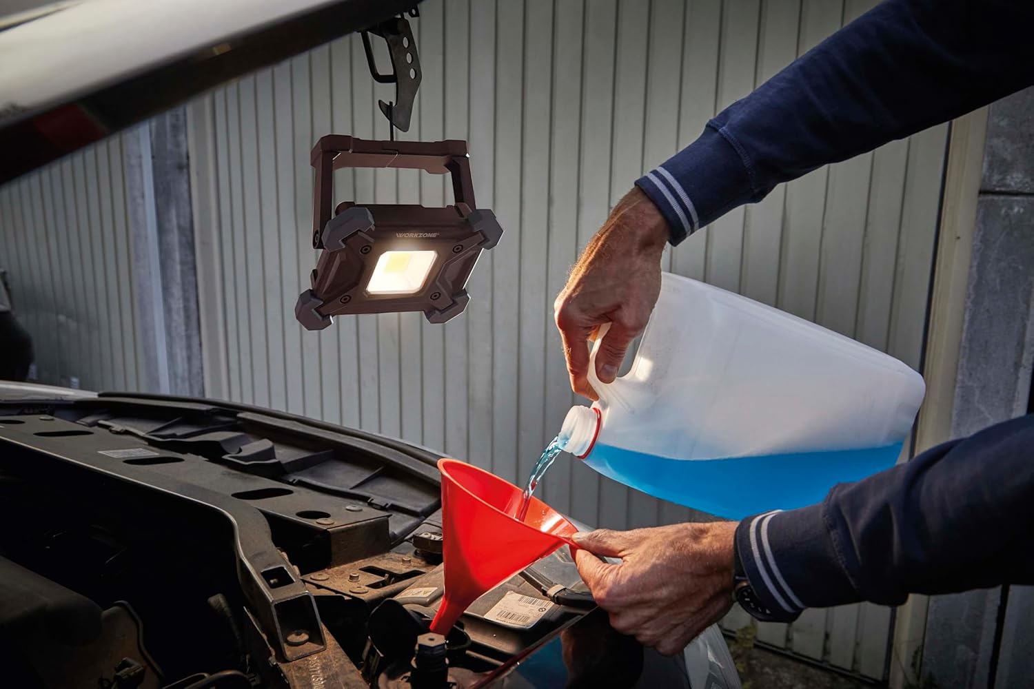 Work light hanging under a car hood, illuminating engine
