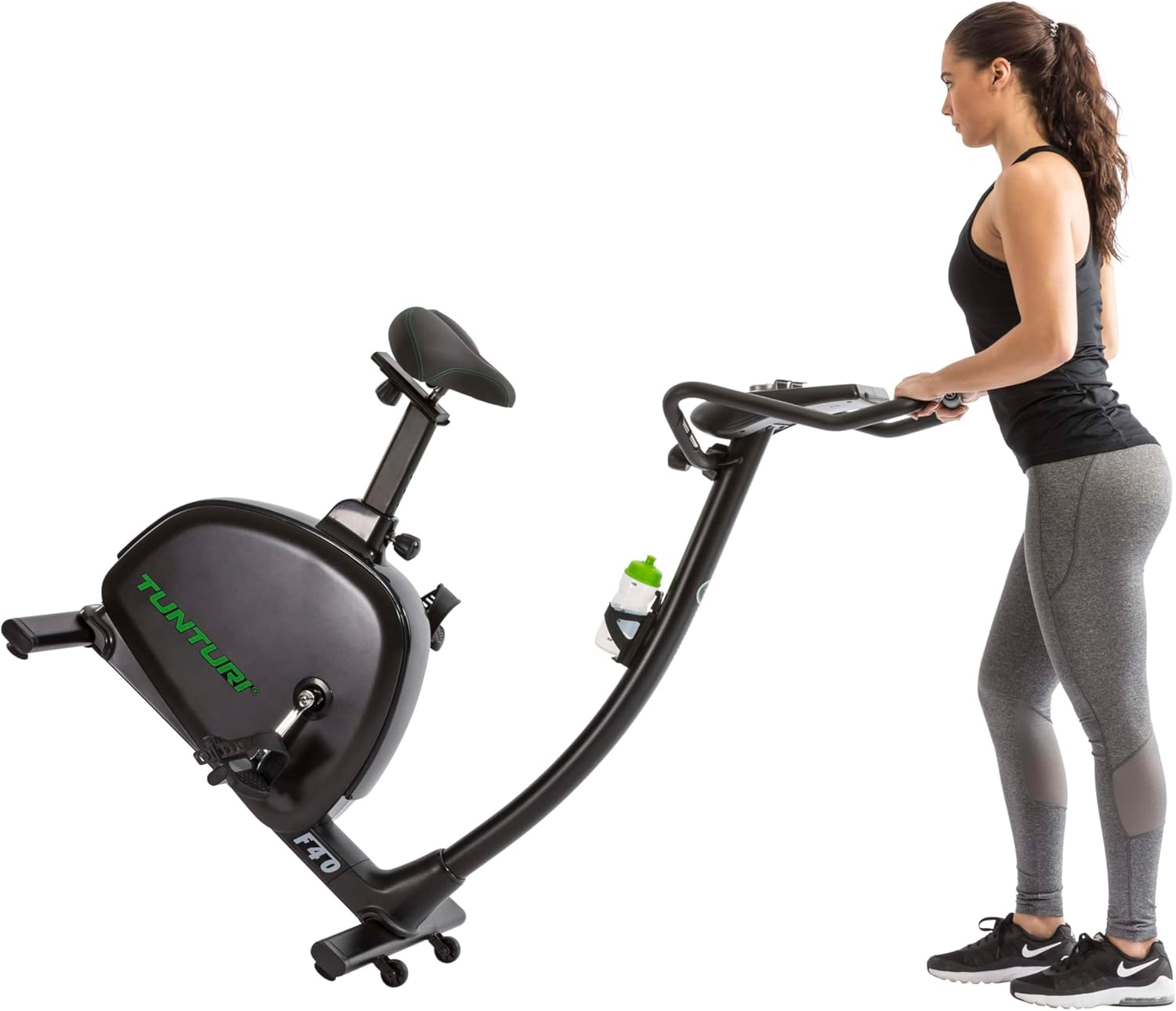 User tilting the Tunturi F40 Competence Series Upright Exercise Bike to engage the transport wheels for easy movement.
