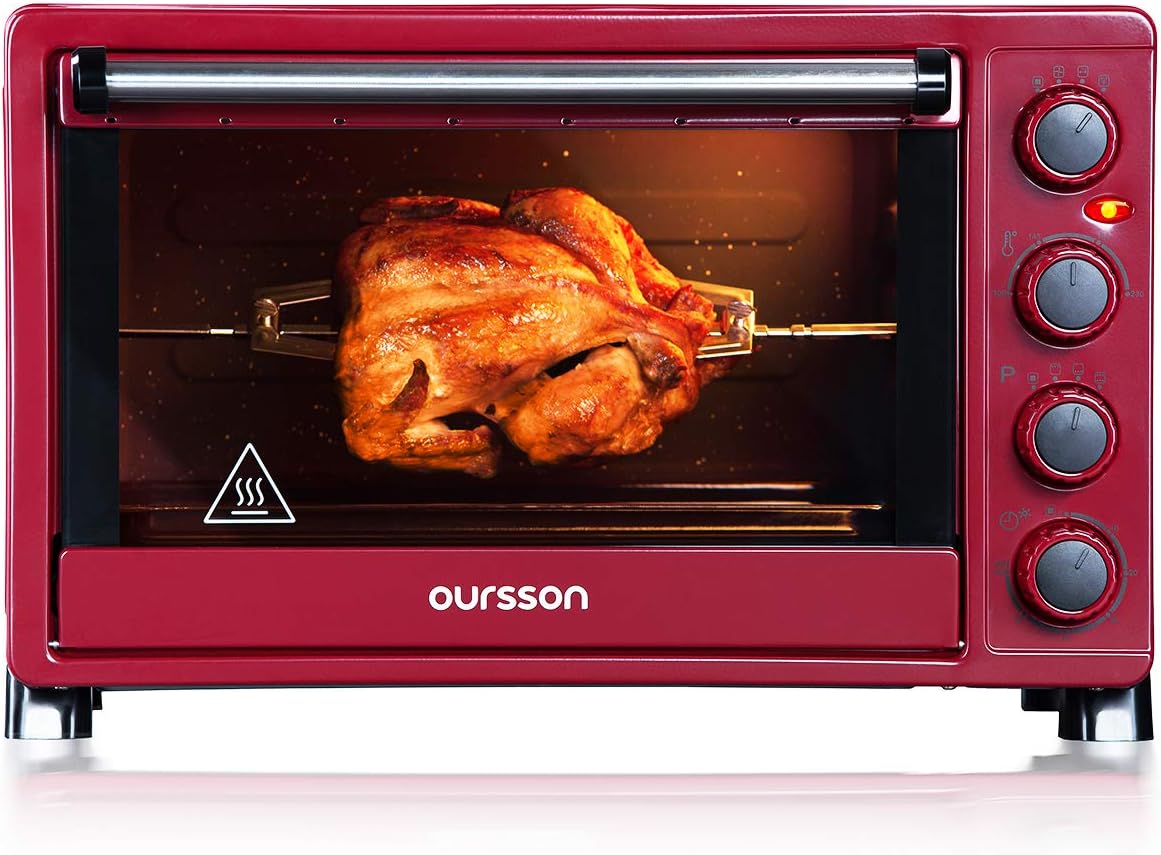 A whole chicken roasting on the rotisserie spit inside the Oursson MO3020/DC Mini Electric Convection Oven