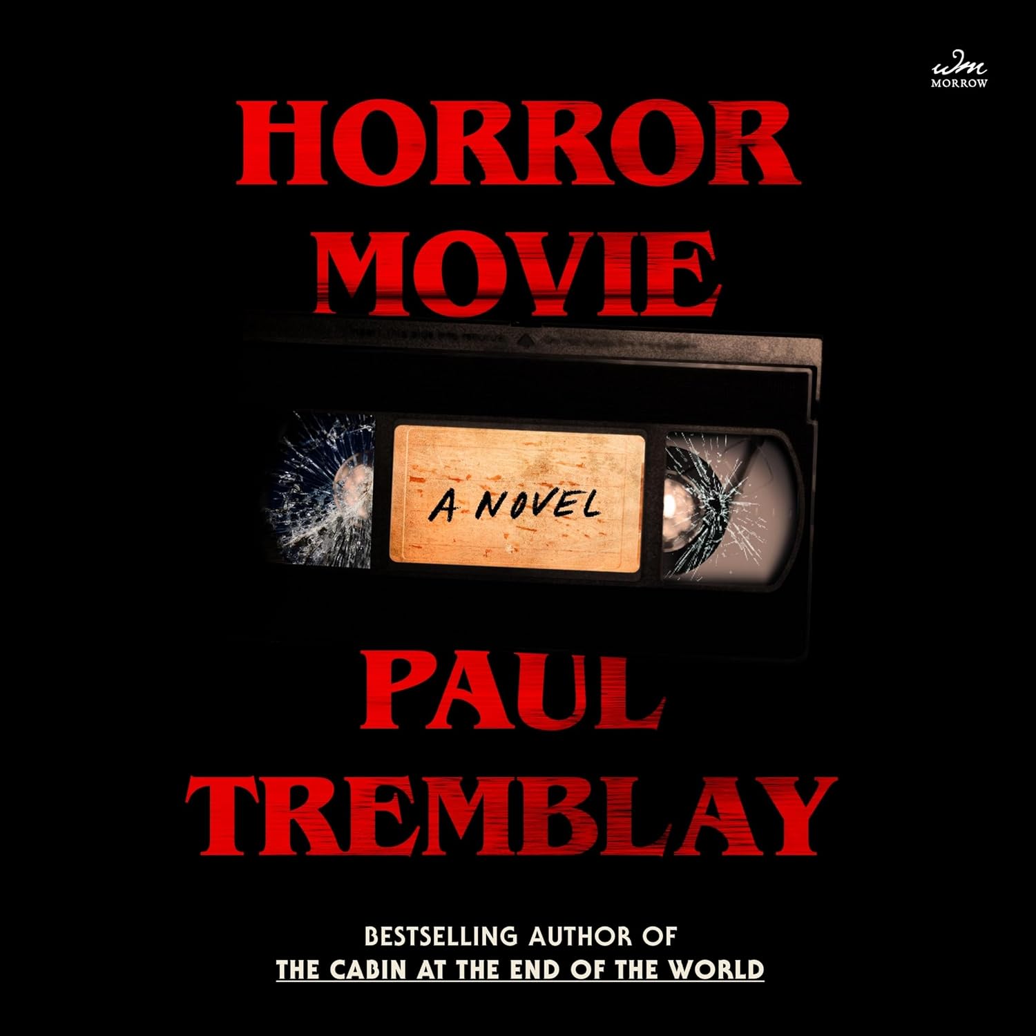 Horror Movie's cover. There is red text at the top that says 'Horror Movie' and a black VHS tape with cracked clear plastic and a dirty brown label that says 'A Novel' in black font reminiscent of writing with a marker. At the bottom is large red text that says 'Paul Tremblay', and smaller white text that says 'Bestselling Author of The Cabin At The End of The World' 