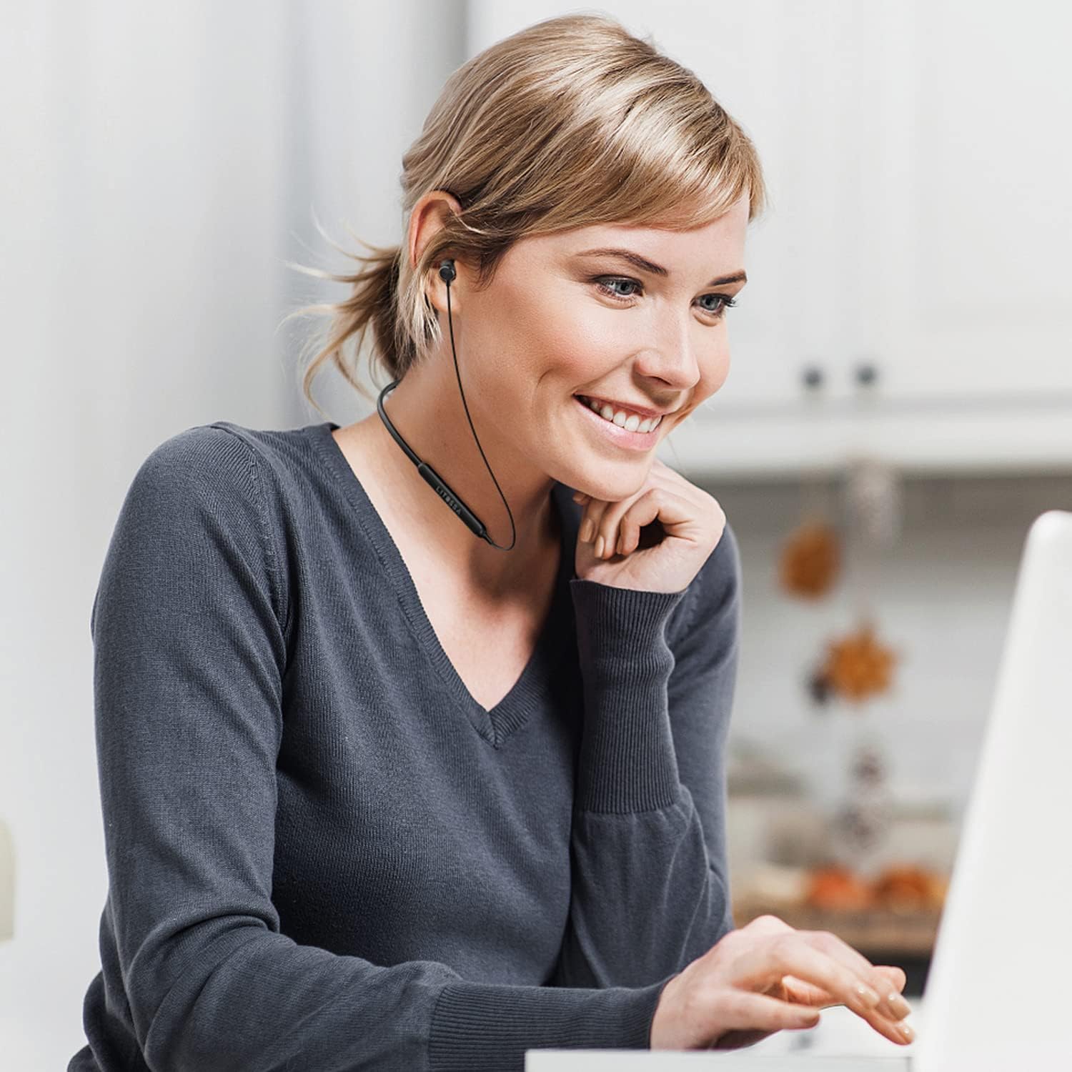 Woman wearing LITOSSA neckband headphones while working on a laptop