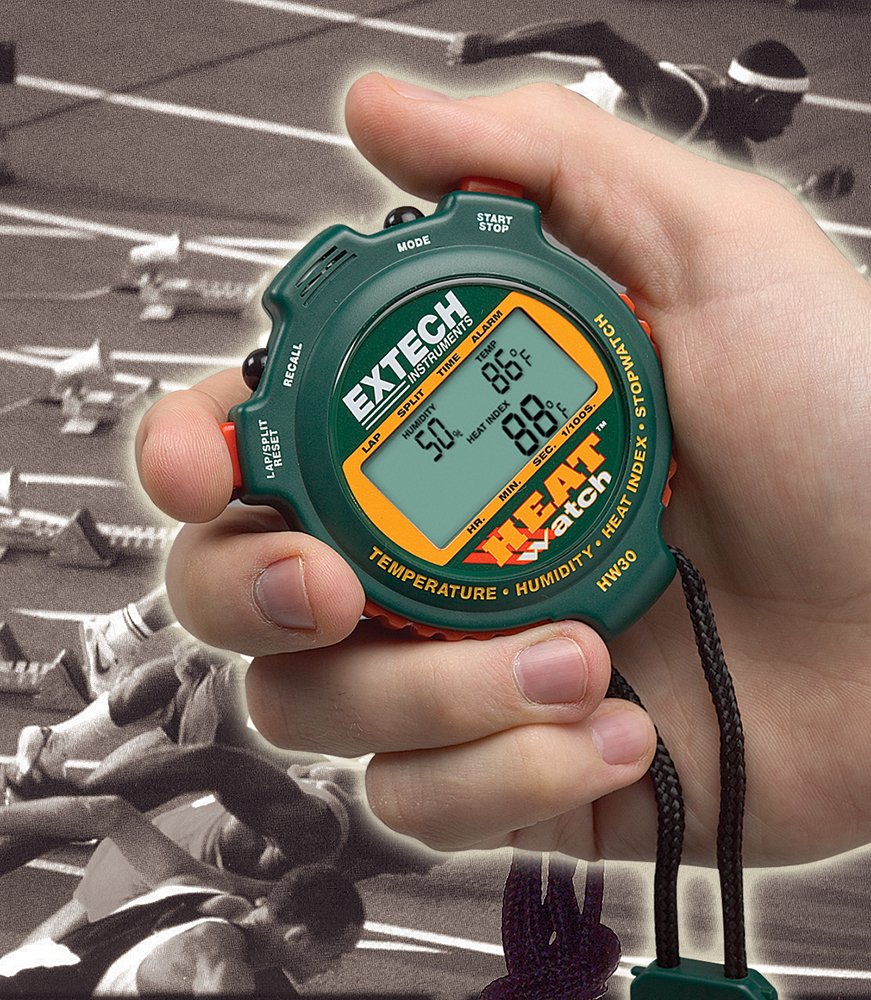 Hand holding Extech HW30 HeatWatch stopwatch on a track field background