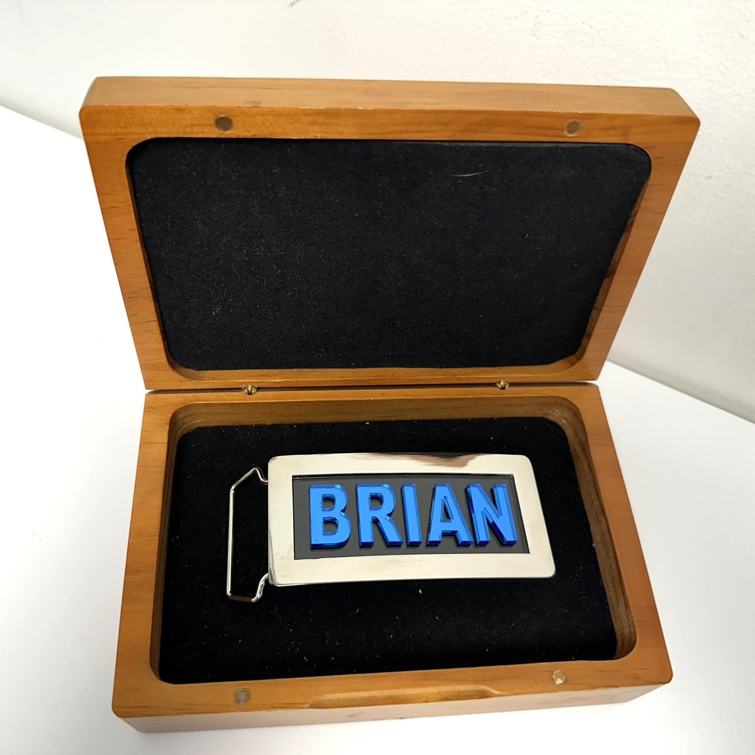 Personalize your attire with an adjustable chrome metal belt buckle, featuring a silver finish and laser-cut blue block letters. Choose any name for this made-to-order men's clothing accessory.