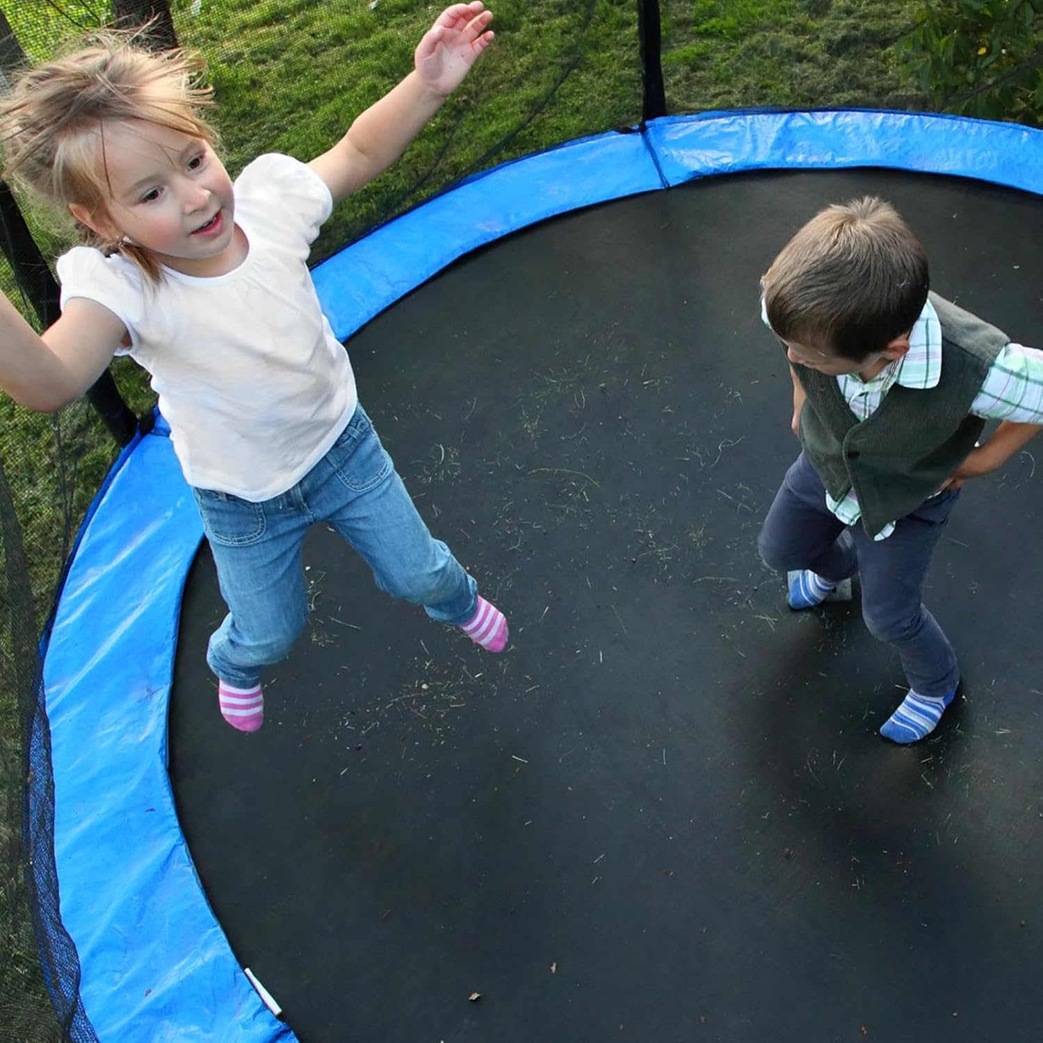 Two children jumping on a trampoline with blue safety padding installed.