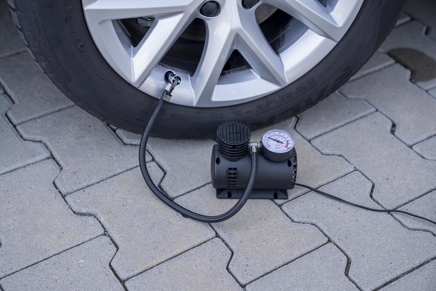Unitec Cartrend 10924 Portable Air Compressor connected to a car tire valve for inflation.