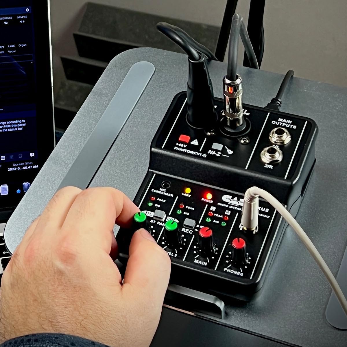 Hand adjusting a knob on the CAD Audio MXU2 mixer during use