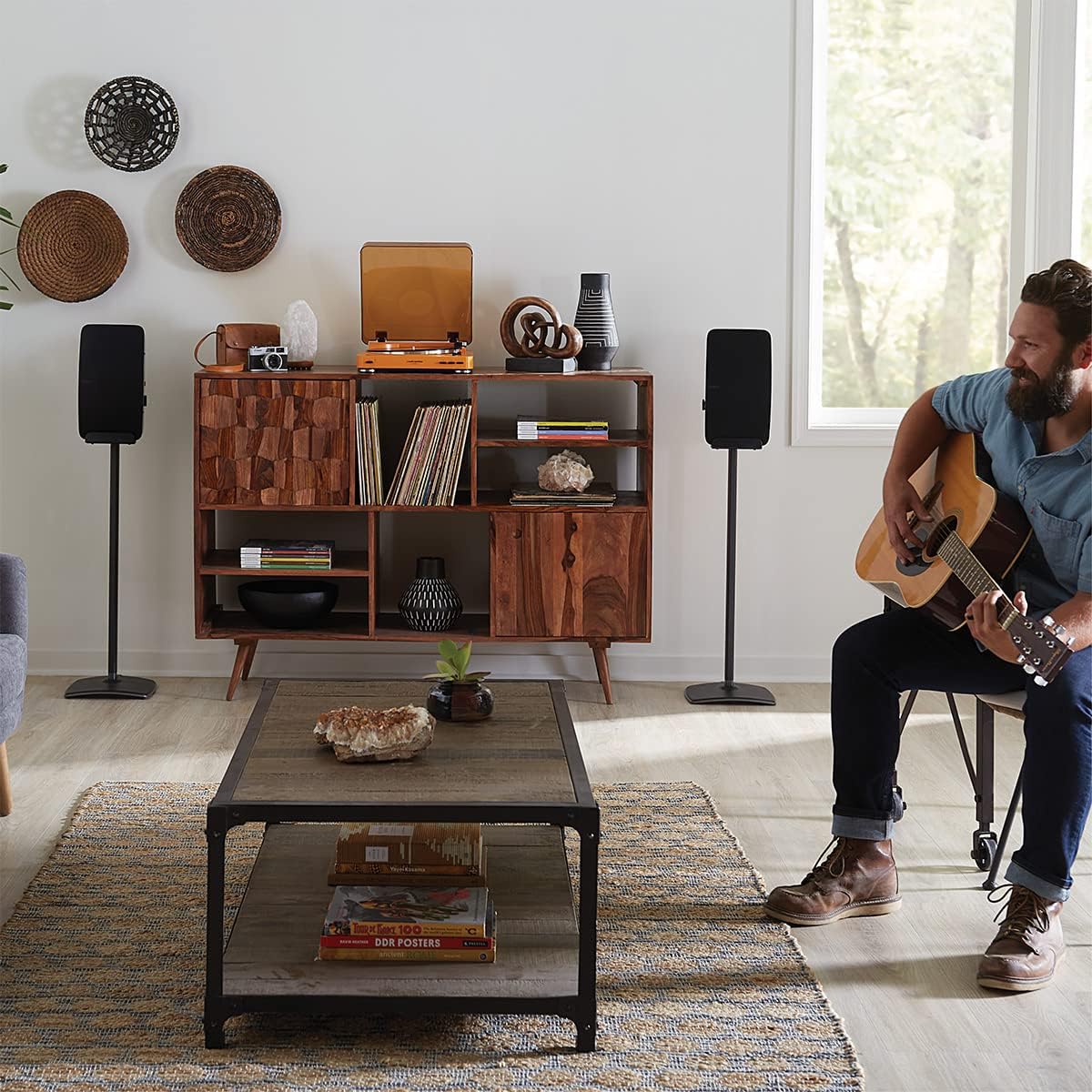 Person playing guitar with two SANUS speaker stands in the background