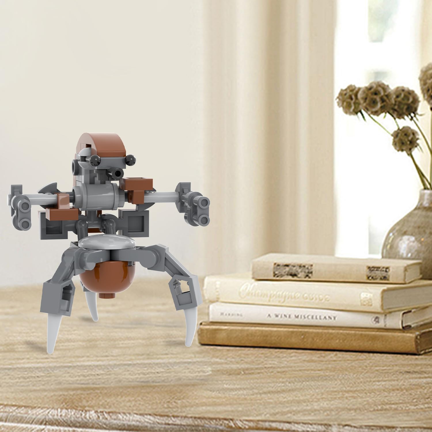 The assembled MOOXI-MOC Destroyer Droideka model displayed on a wooden table next to books and a plant, showcasing its completed form.