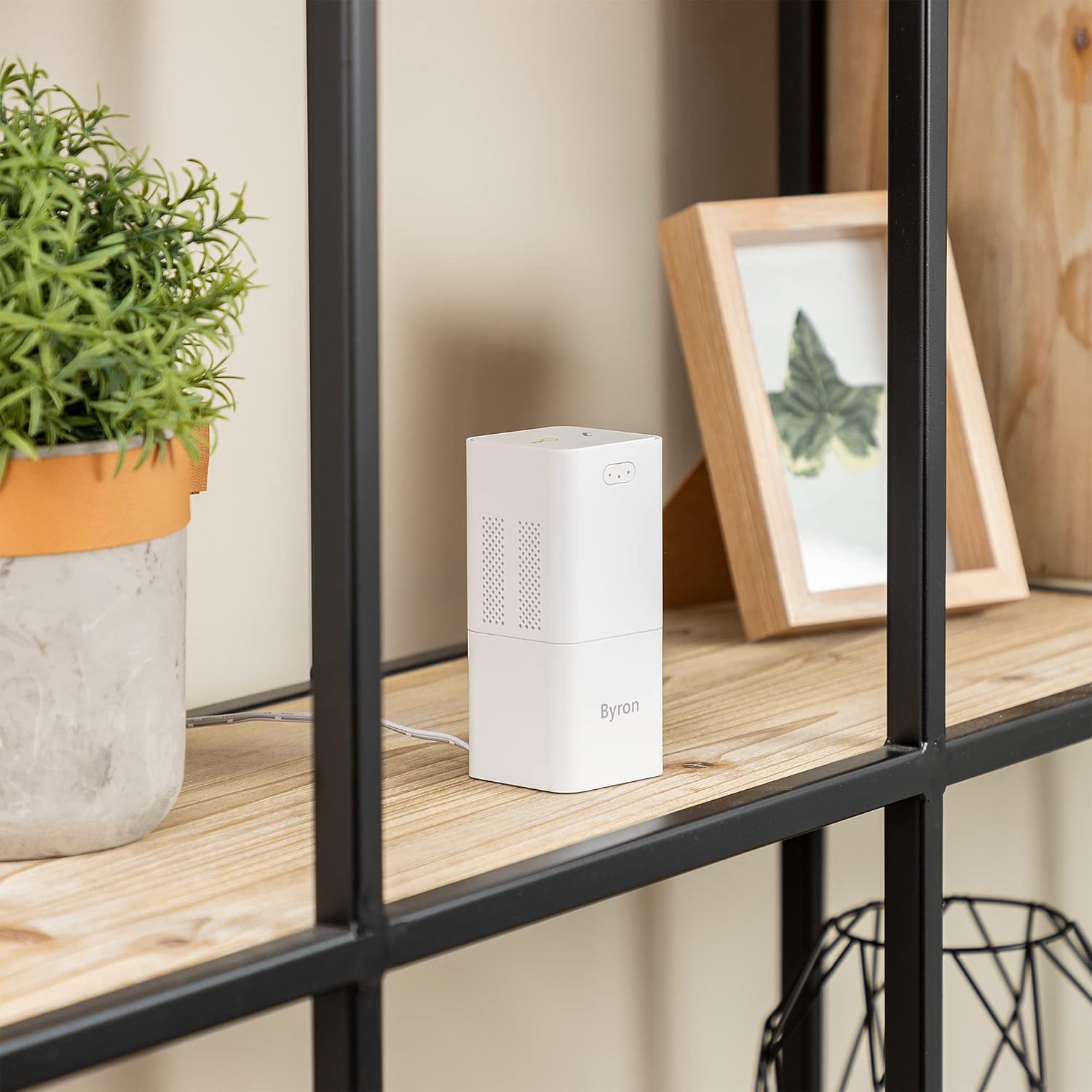 Byron DIC-21525 Indoor unit placed on a wooden shelf next to a plant and picture frame.