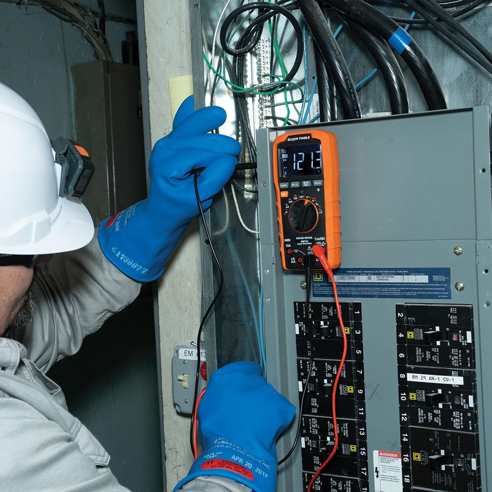 Electrician using the Klein Tools MM720 Digital Multimeter to measure voltage in an electrical panel.