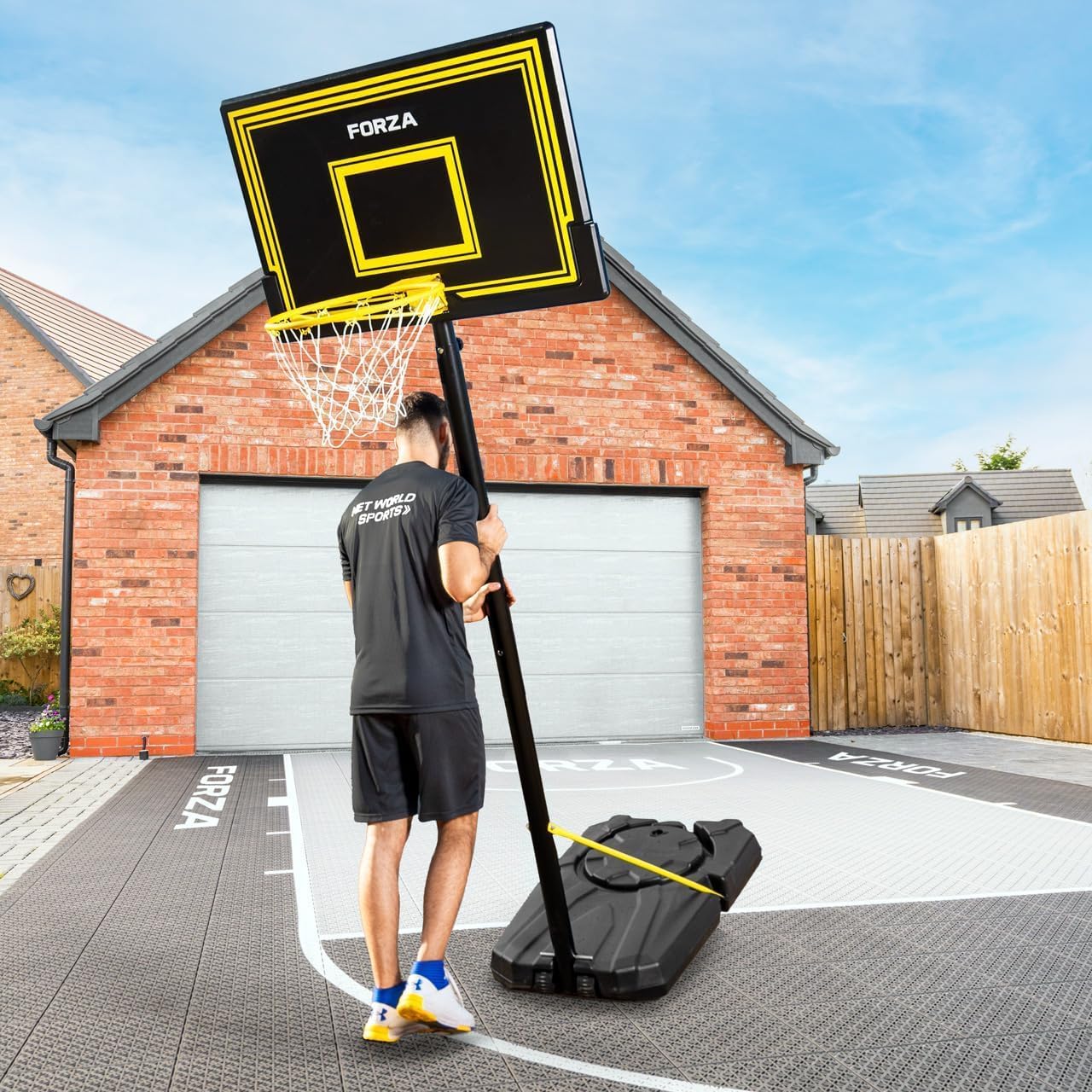 A person moving the FORZA basketball hoop system using its wheeled base.