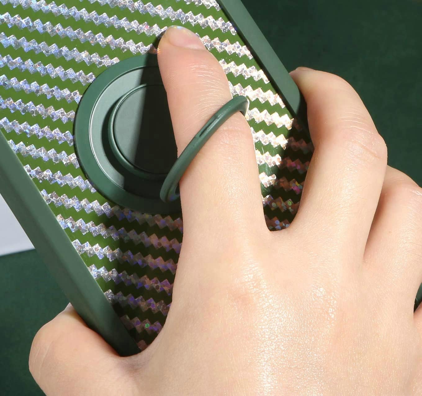 Hand holding phone with finger through the 360-degree rotating ring holder.