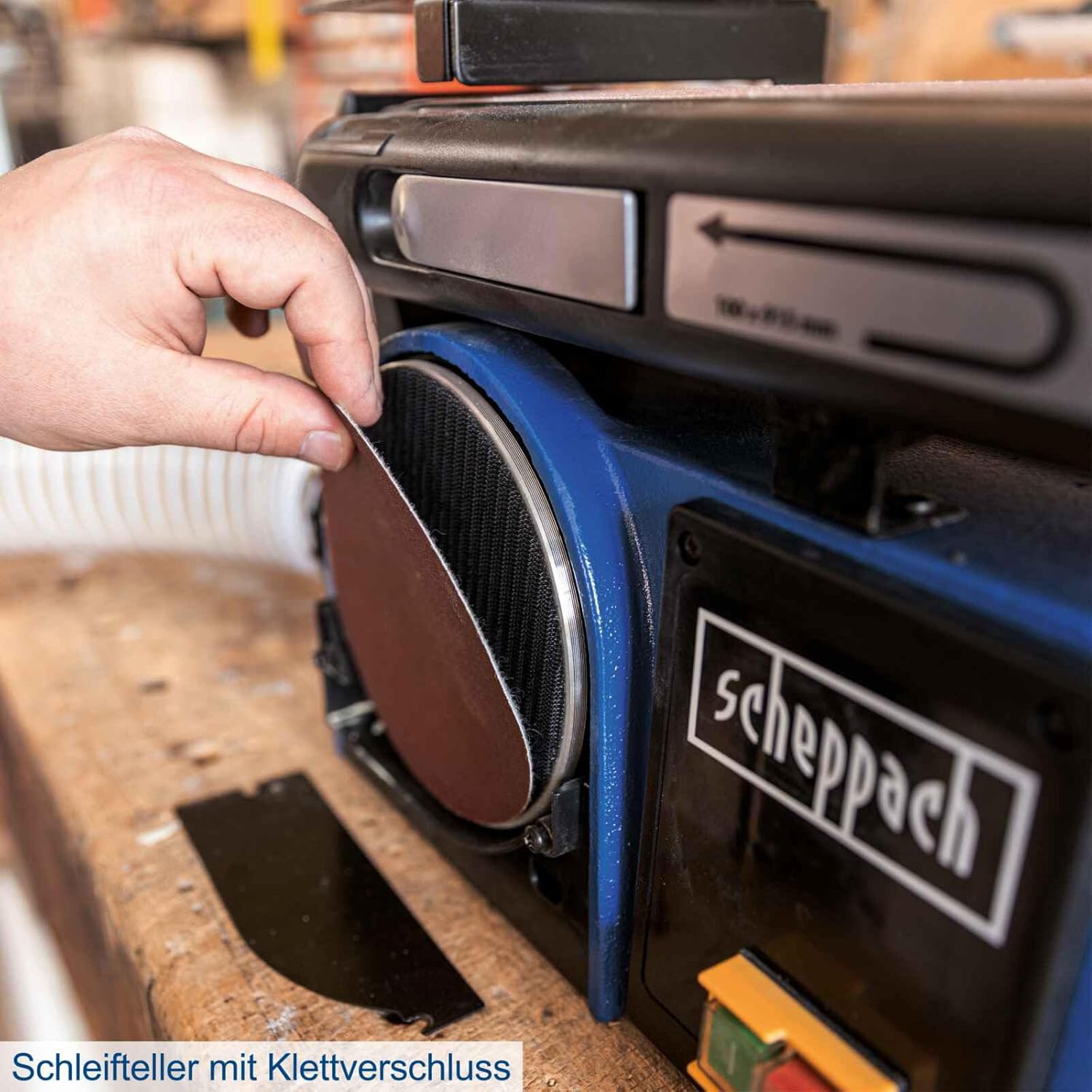 Hand peeling off a sanding disc from the disc sander