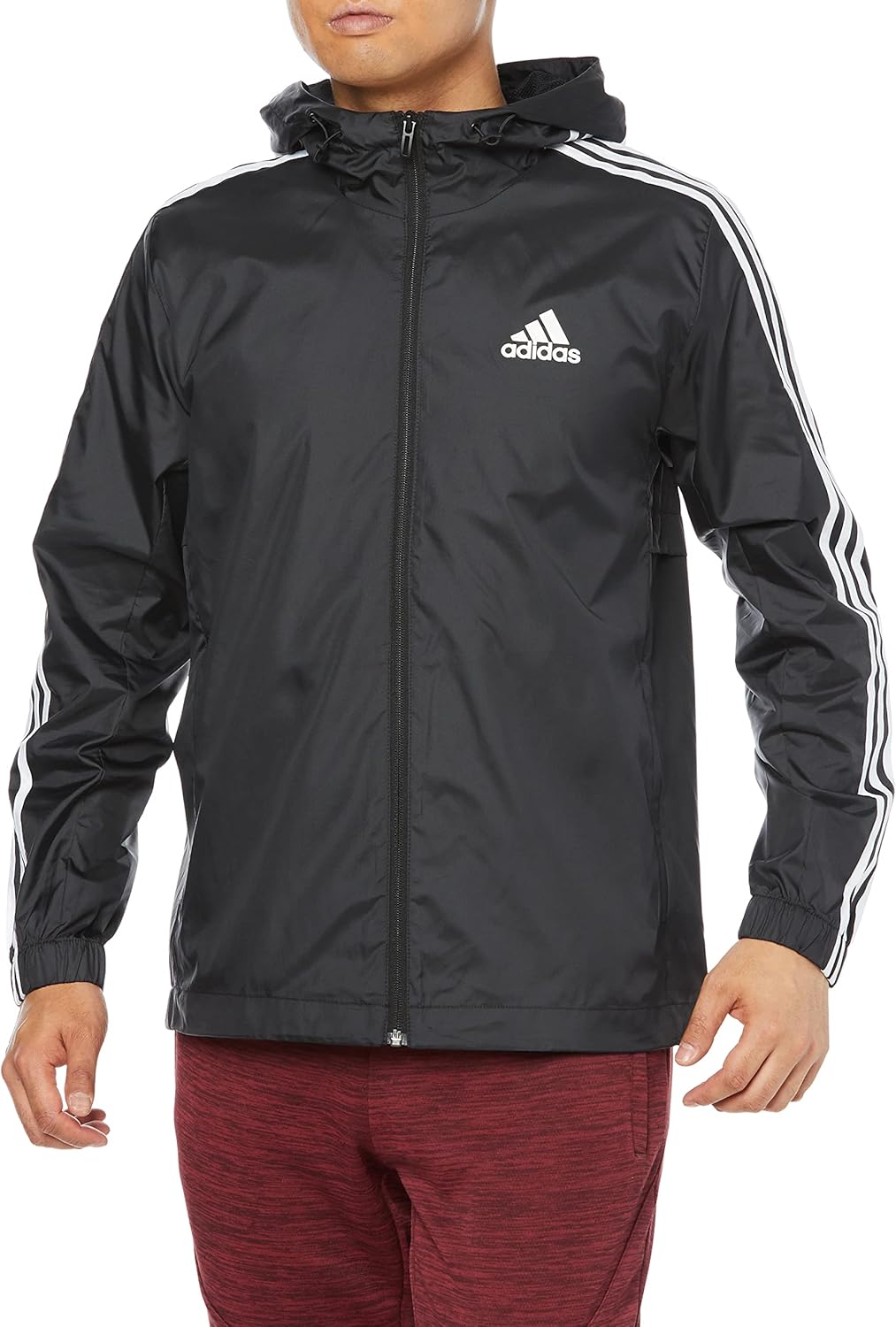 ด้านหน้า view of the Adidas Essentials 3-Stripes Woven Windbreaker in black, worn by a male model.