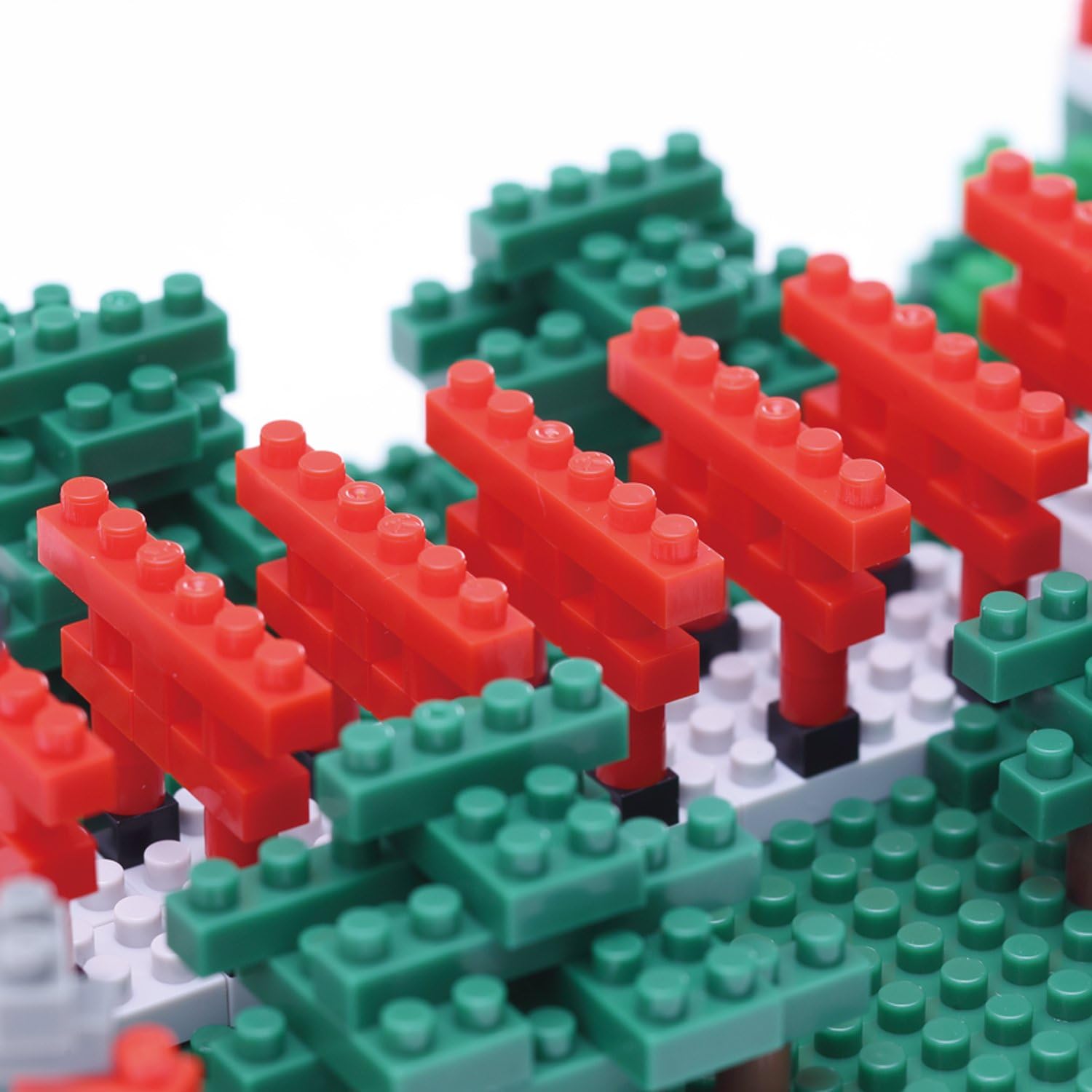 Close-up view of the red torii gate tunnel section of the NanoBlock Inari Shrine model, showing multiple red gates and green foliage.