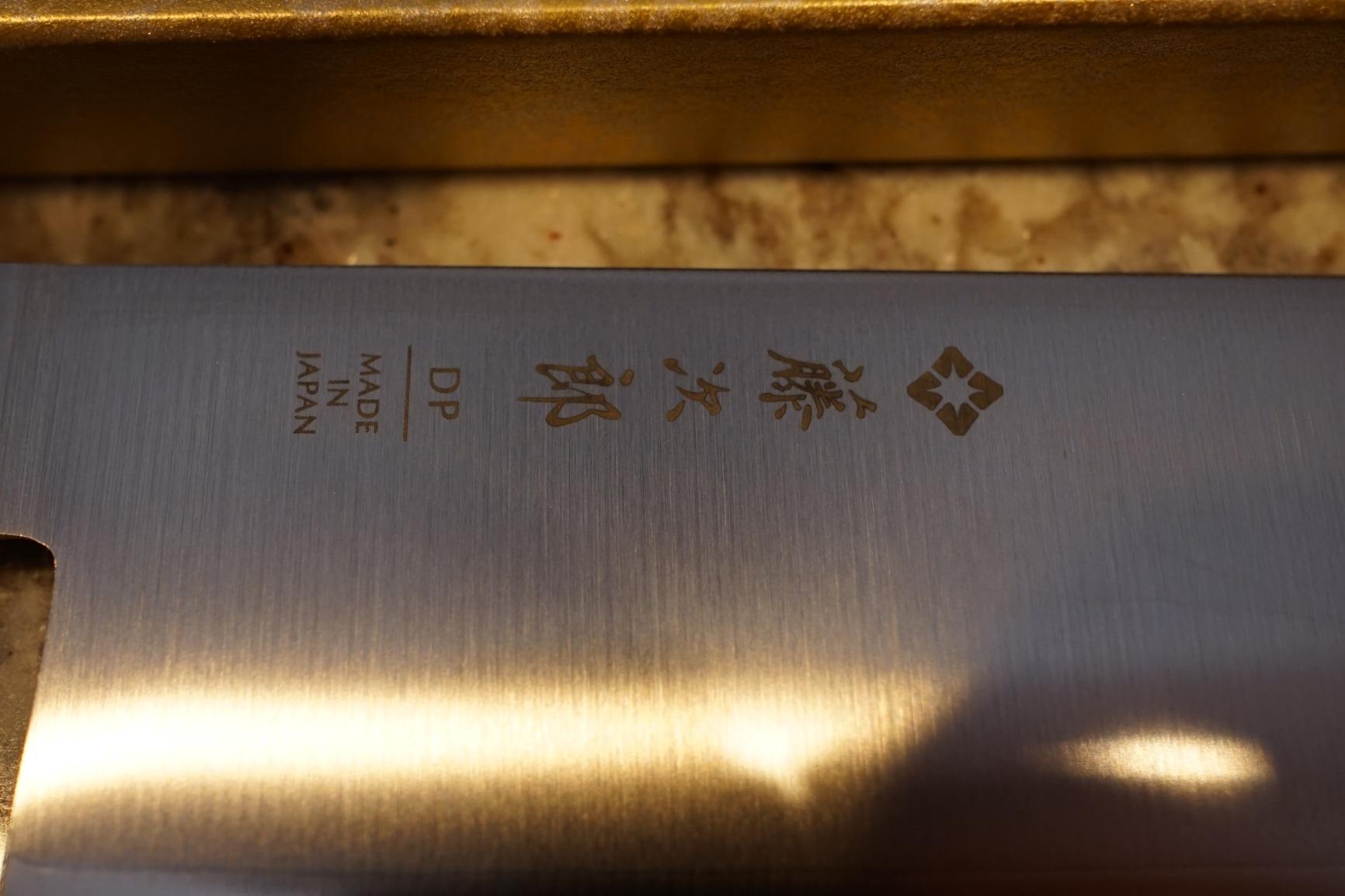 Close up of a nakiri blade slicing through a stack of vegetables