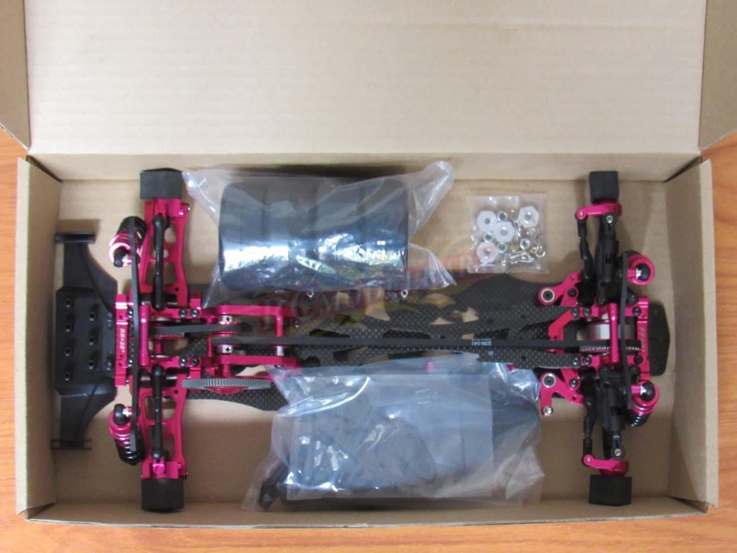 Components of the Hobbypower F124A kit laid out in its packaging, including chassis parts, wheels, and small hardware.