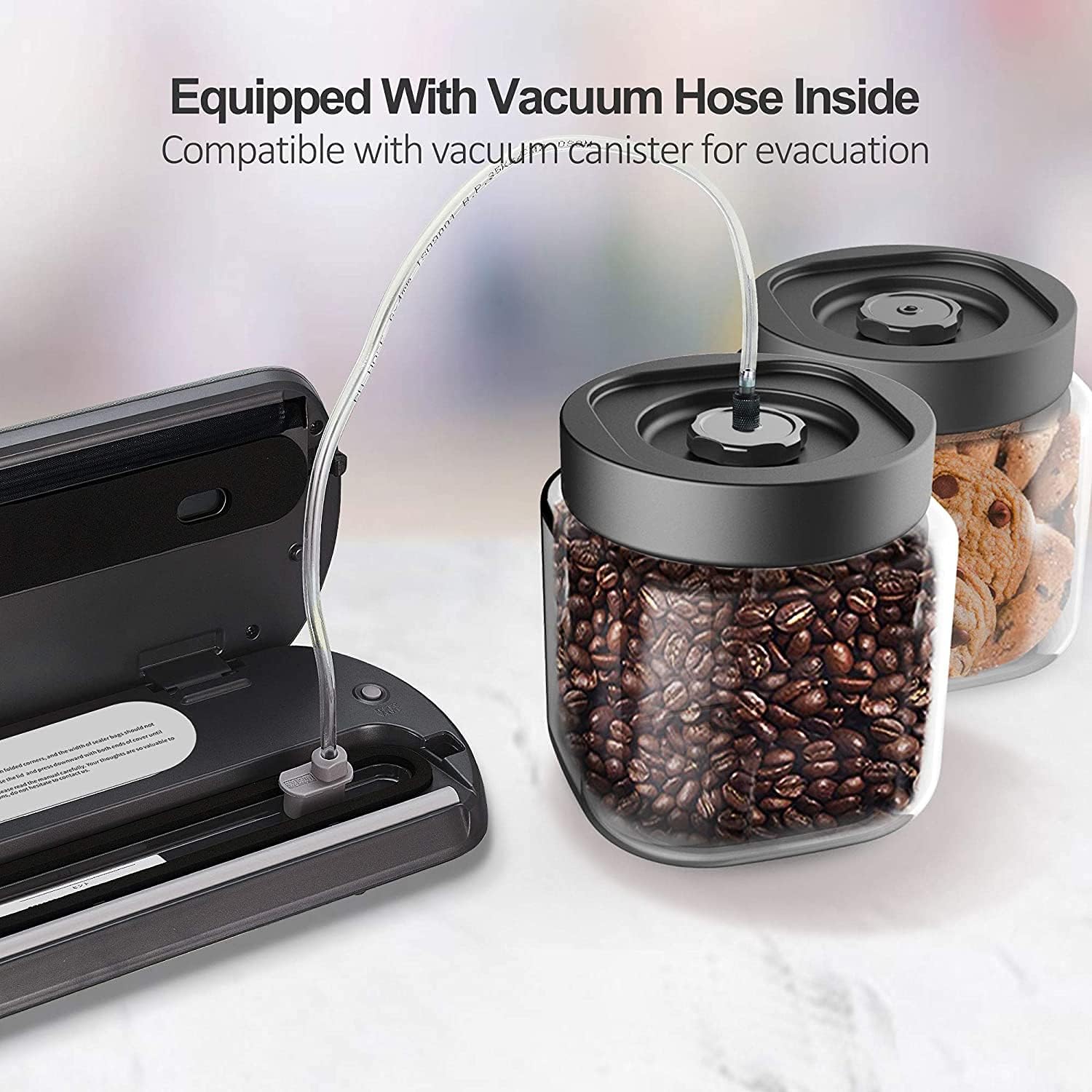 KitchenBoss vacuum sealer connected to a vacuum canister with coffee beans via an external hose.