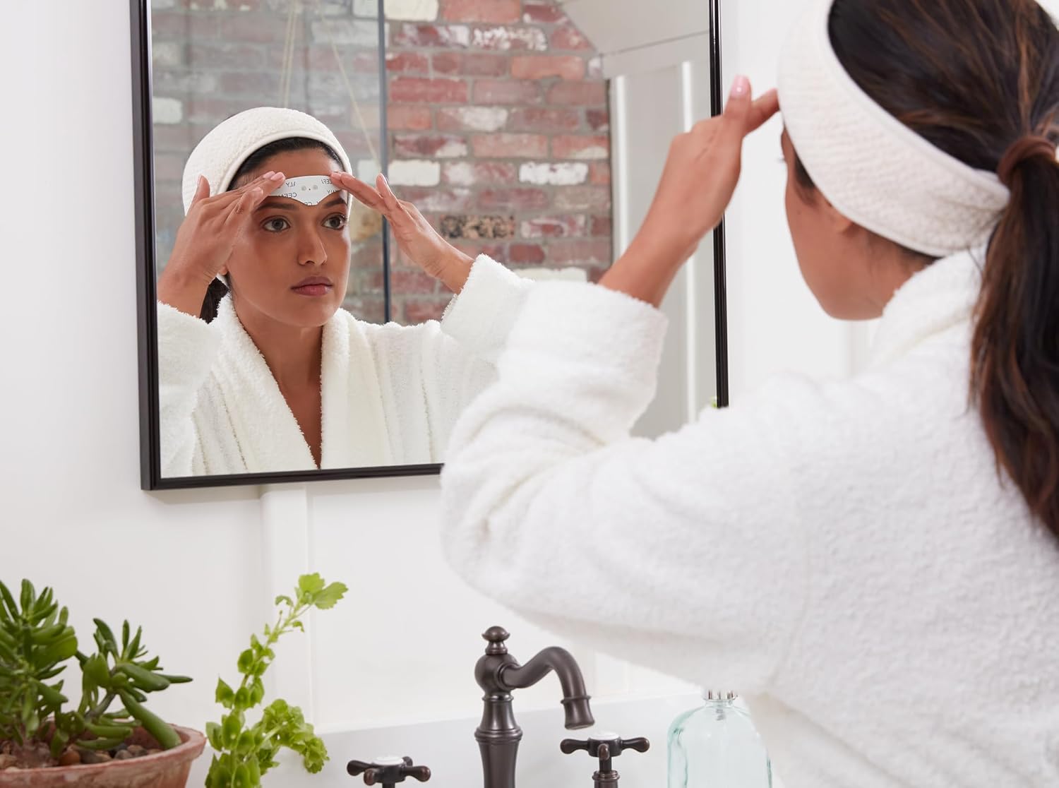 Woman applying Cefaly electrode to forehead