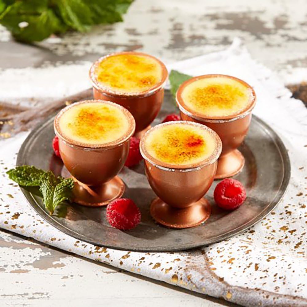 Four Copper Chef Copper Egg XL cups filled with a dessert, possibly creme brulee, garnished with raspberries and mint.