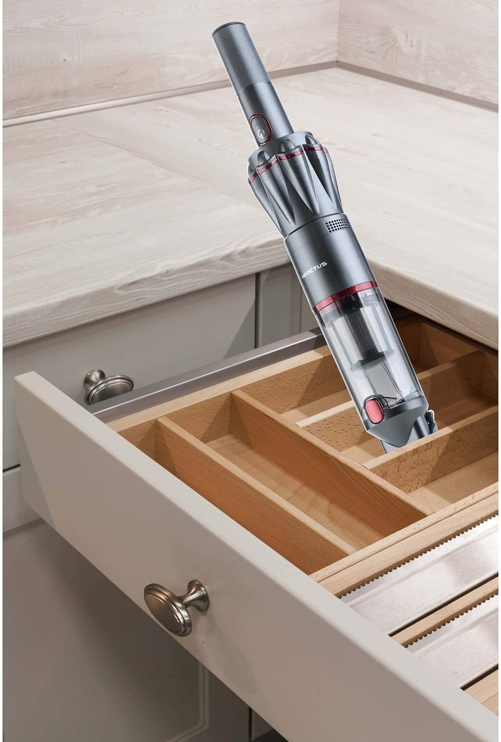 Genius Invictus One handheld vacuum cleaning inside a kitchen drawer