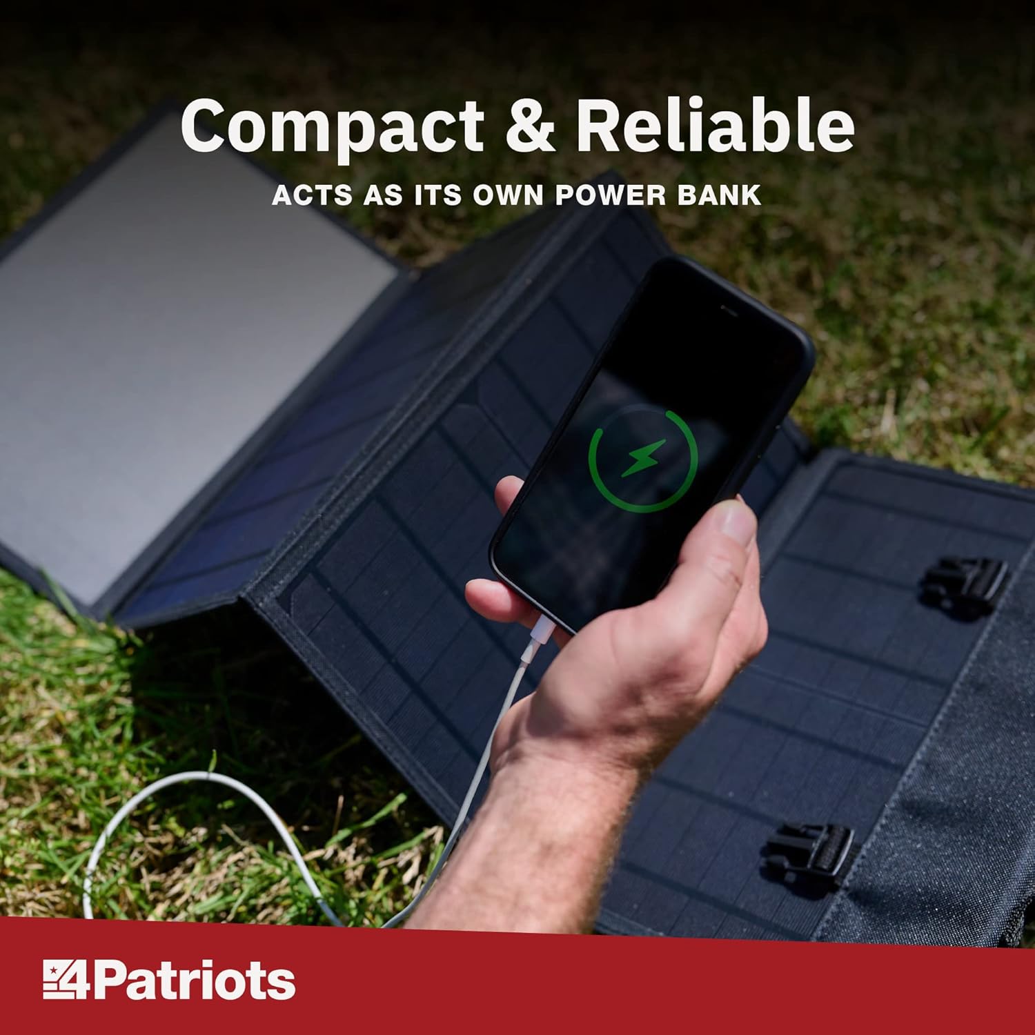A smartphone displaying a charging icon, connected to the 4Patriots solar panel outdoors.