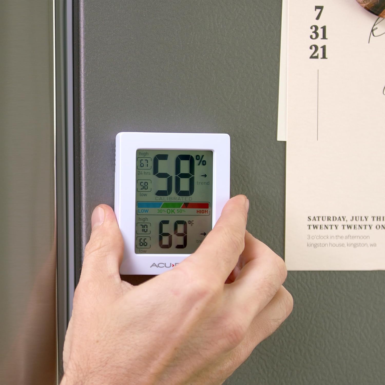 A hand placing the AcuRite Digital Hygrometer and Thermometer onto a metal surface using its magnetic back.