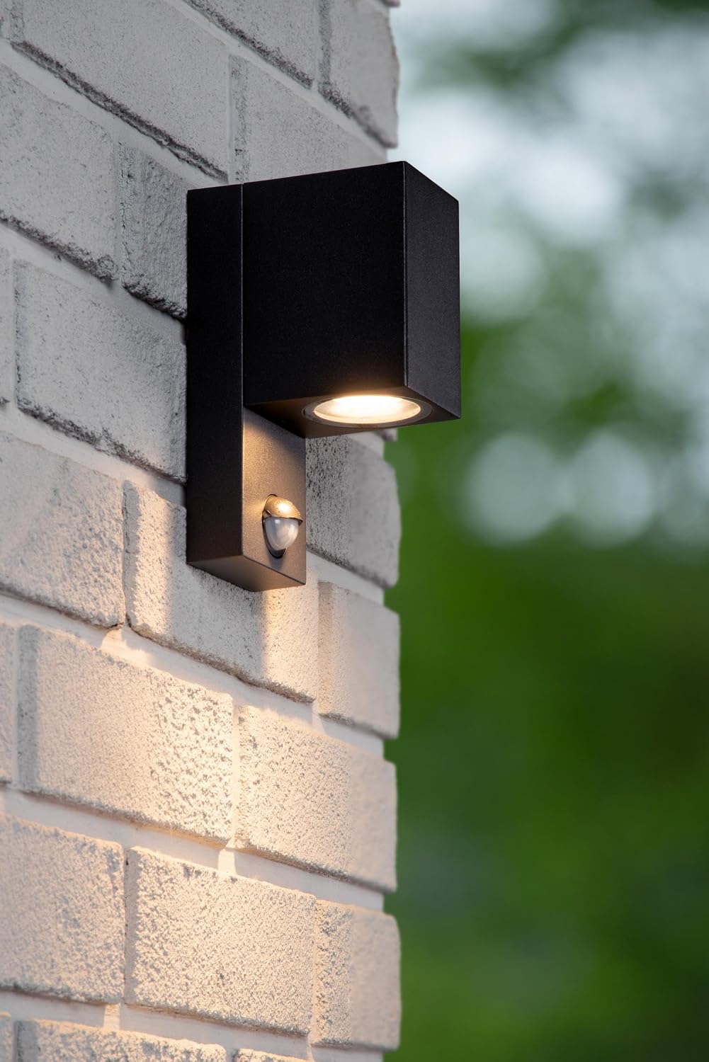 Lucide ZARO IR wall light installed on a brick wall, illuminating downwards.
